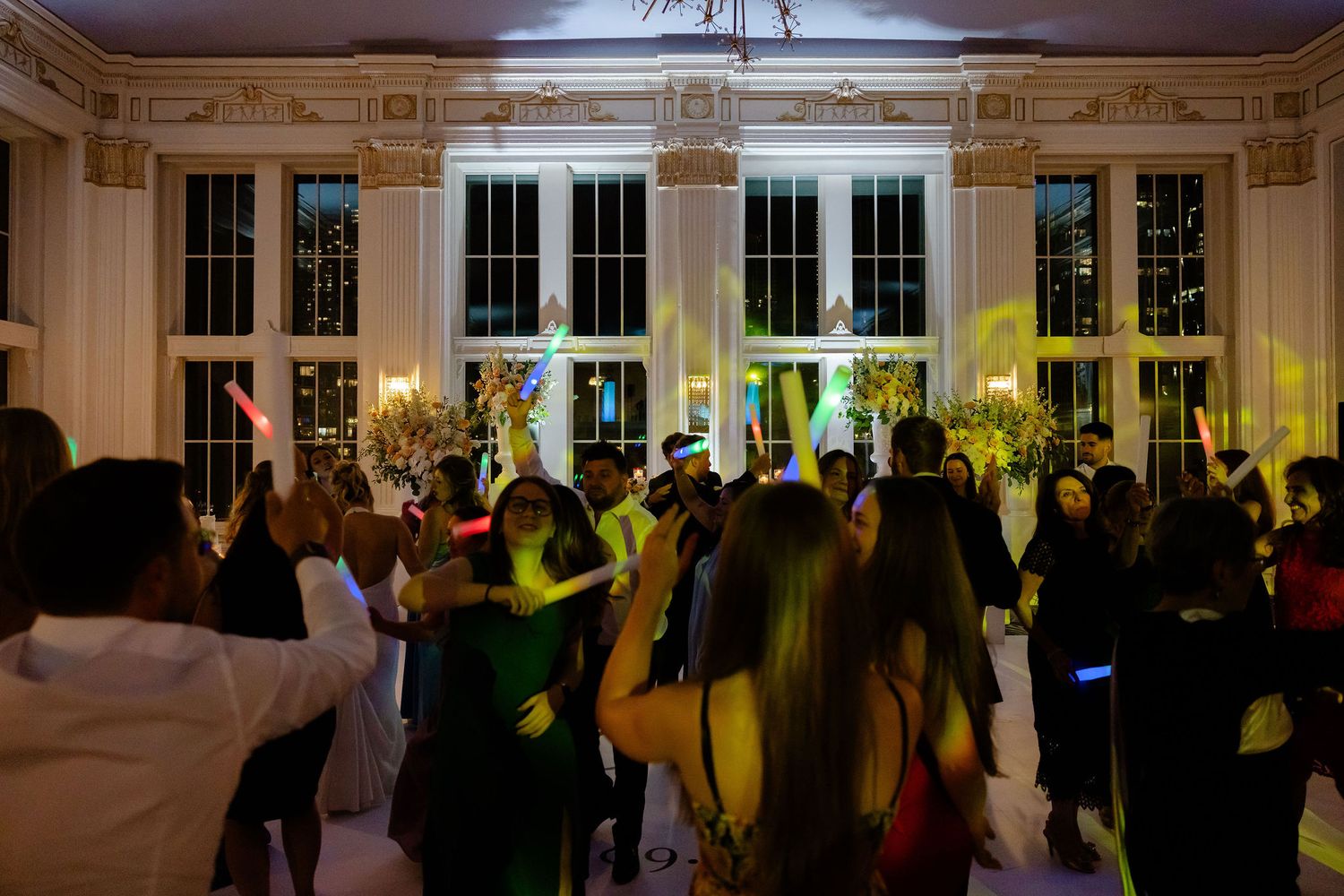 Wedding reception dance floor filled with guests enjoying the celebration in an ornate ballroom.