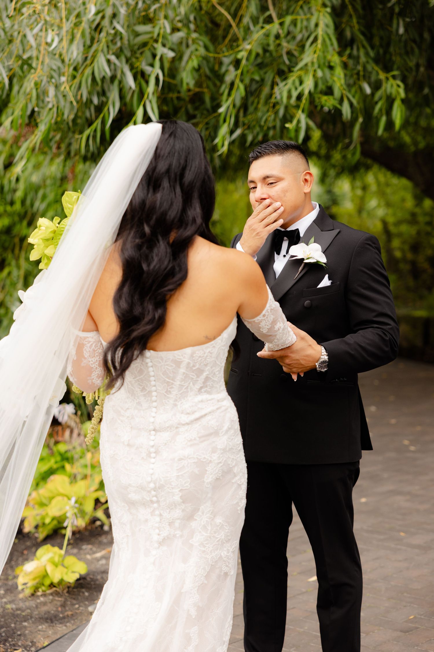 A newlywed couple shares an intimate moment outdoors with greenery in the background during their wedding ceremony.