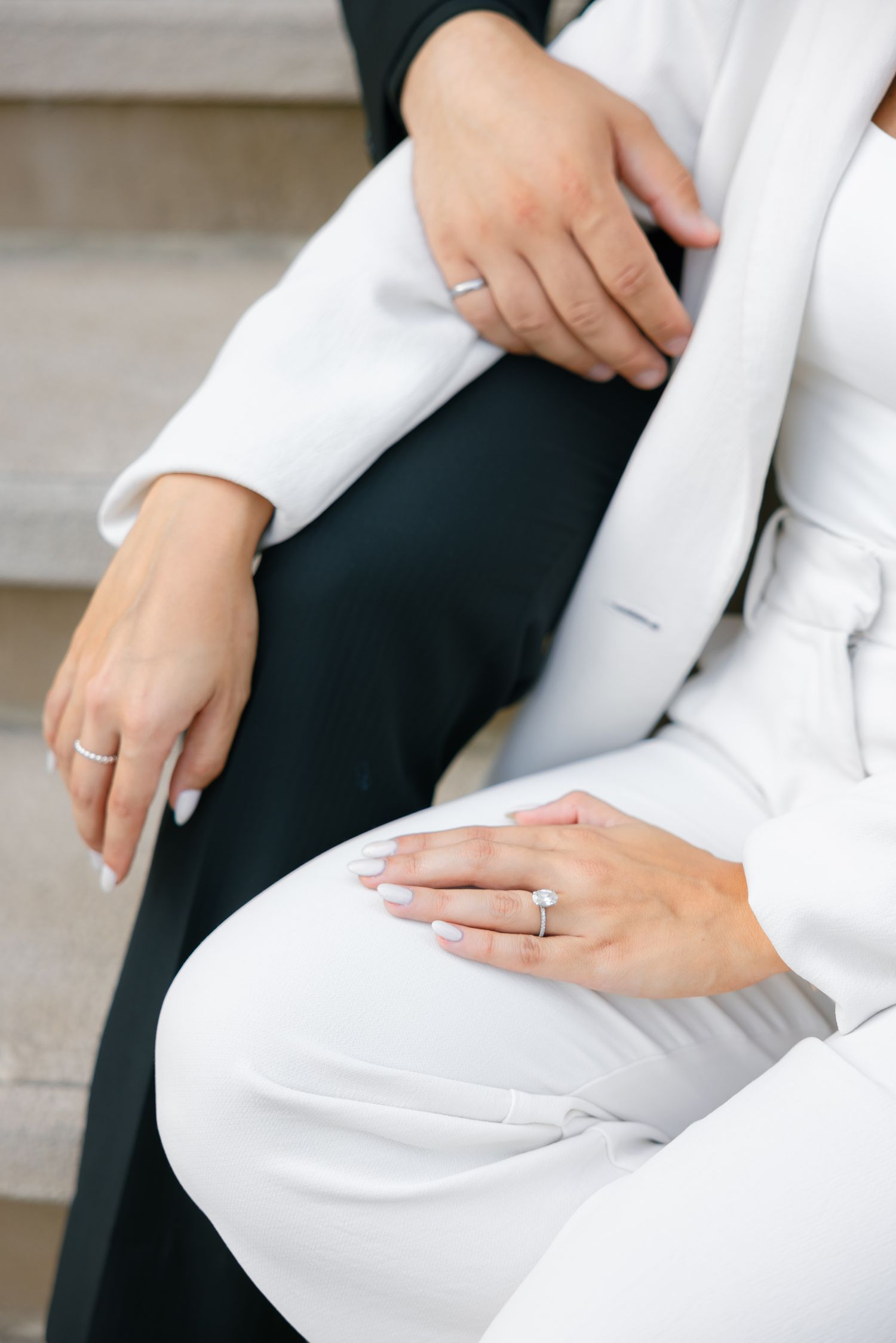 Detail shot of hands wearing matching rings against black and white clothing.