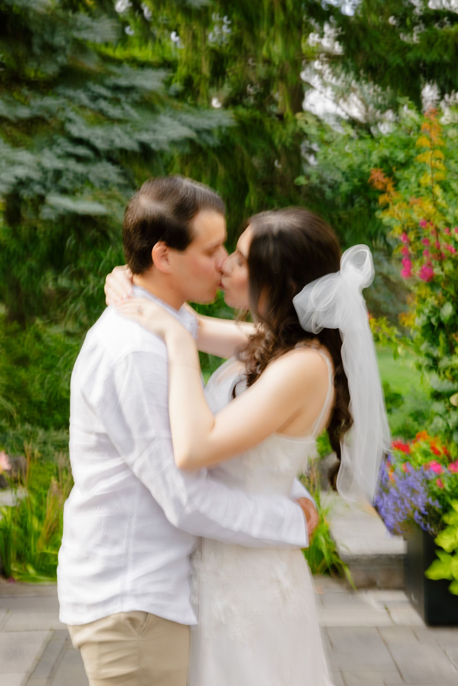 A soft focus romantic moment between newlyweds in a garden setting with colorful flowers.