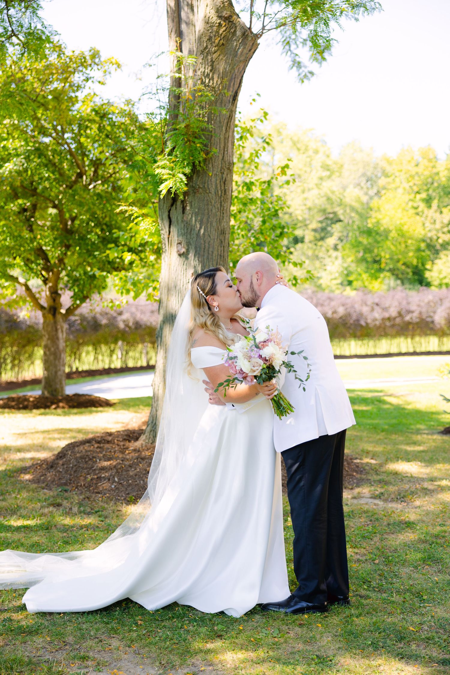 Romantic garden wedding moment with bride's dress trailing beautifully on grass.