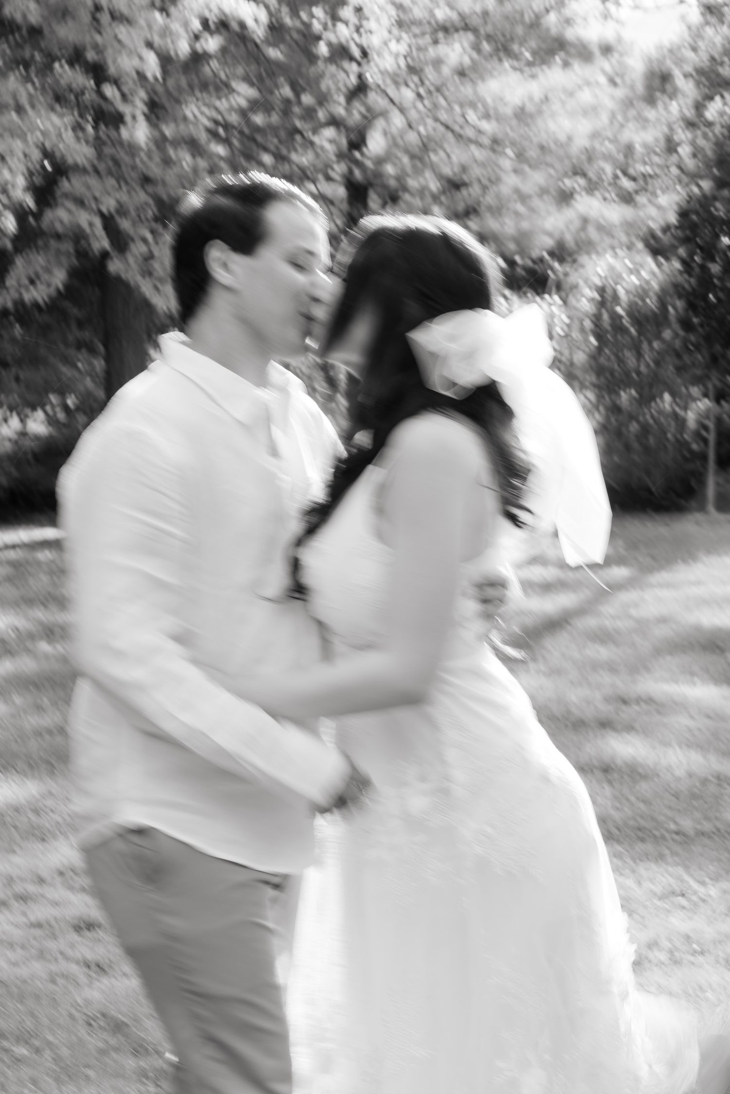 A black and white capture of a romantic moment between newlyweds in an outdoor garden setting.
