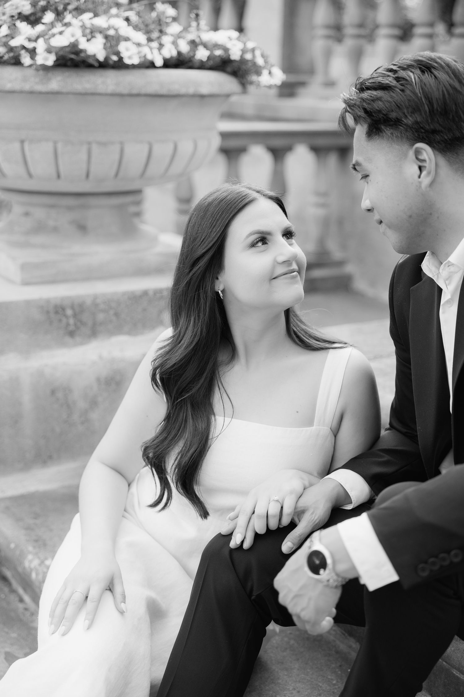 A black and white portrait of a couple sharing an intimate moment on outdoor stone steps.