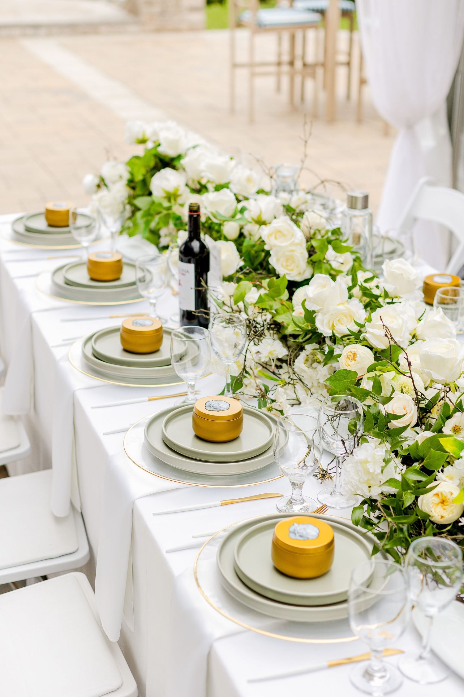 Long wedding reception table with white floral runner and yellow desserts on gray plates.