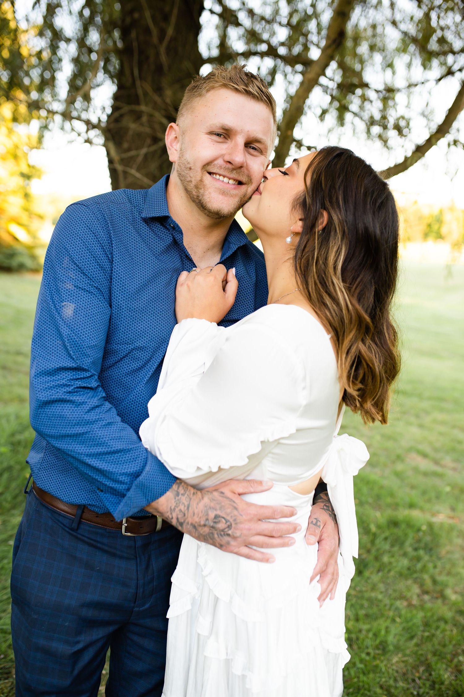 A joyful couple embraces while sharing a romantic moment in a sunny outdoor setting.