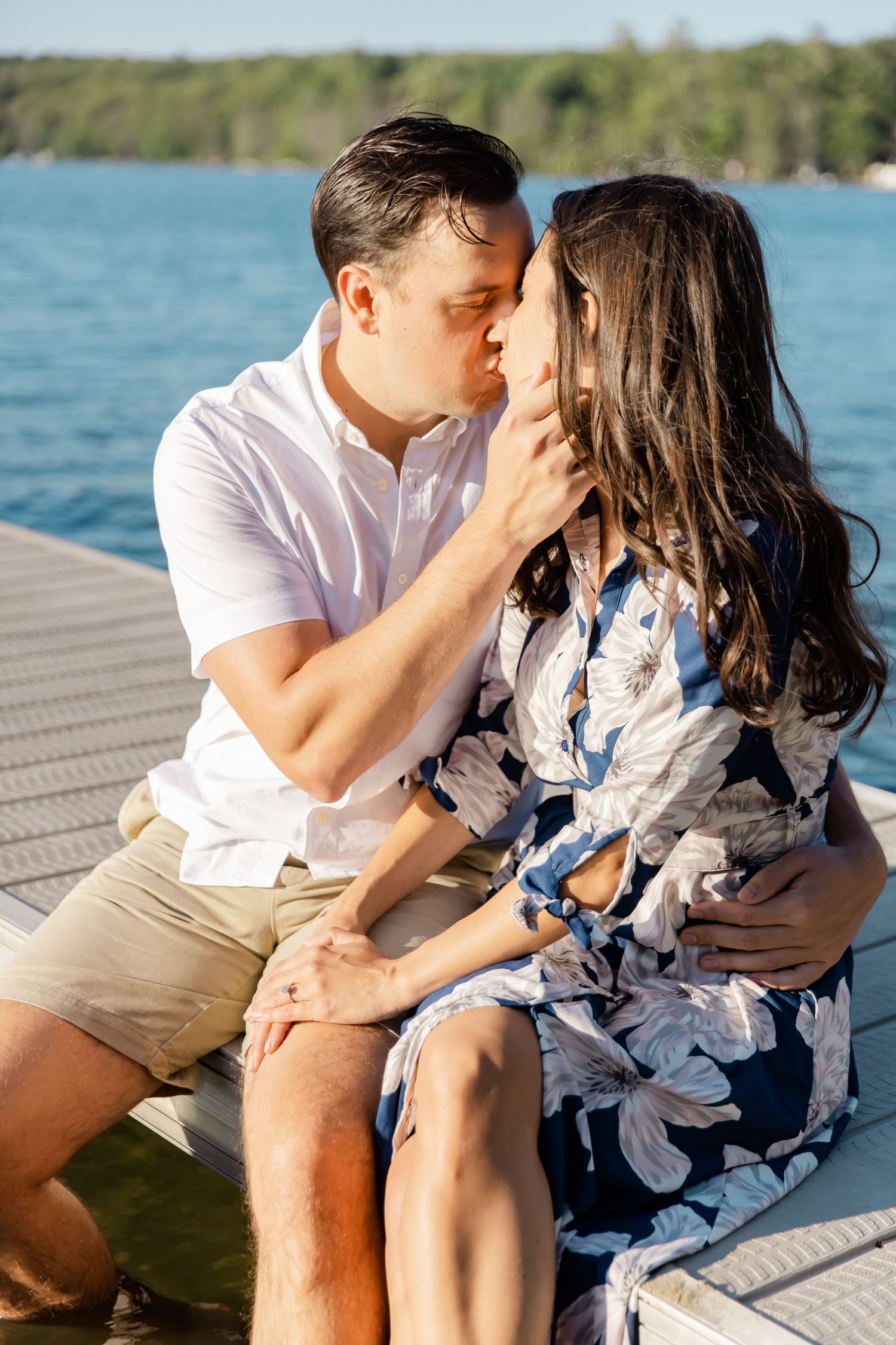 Intimate moment between couple in casual summer attire on lakeside dock.