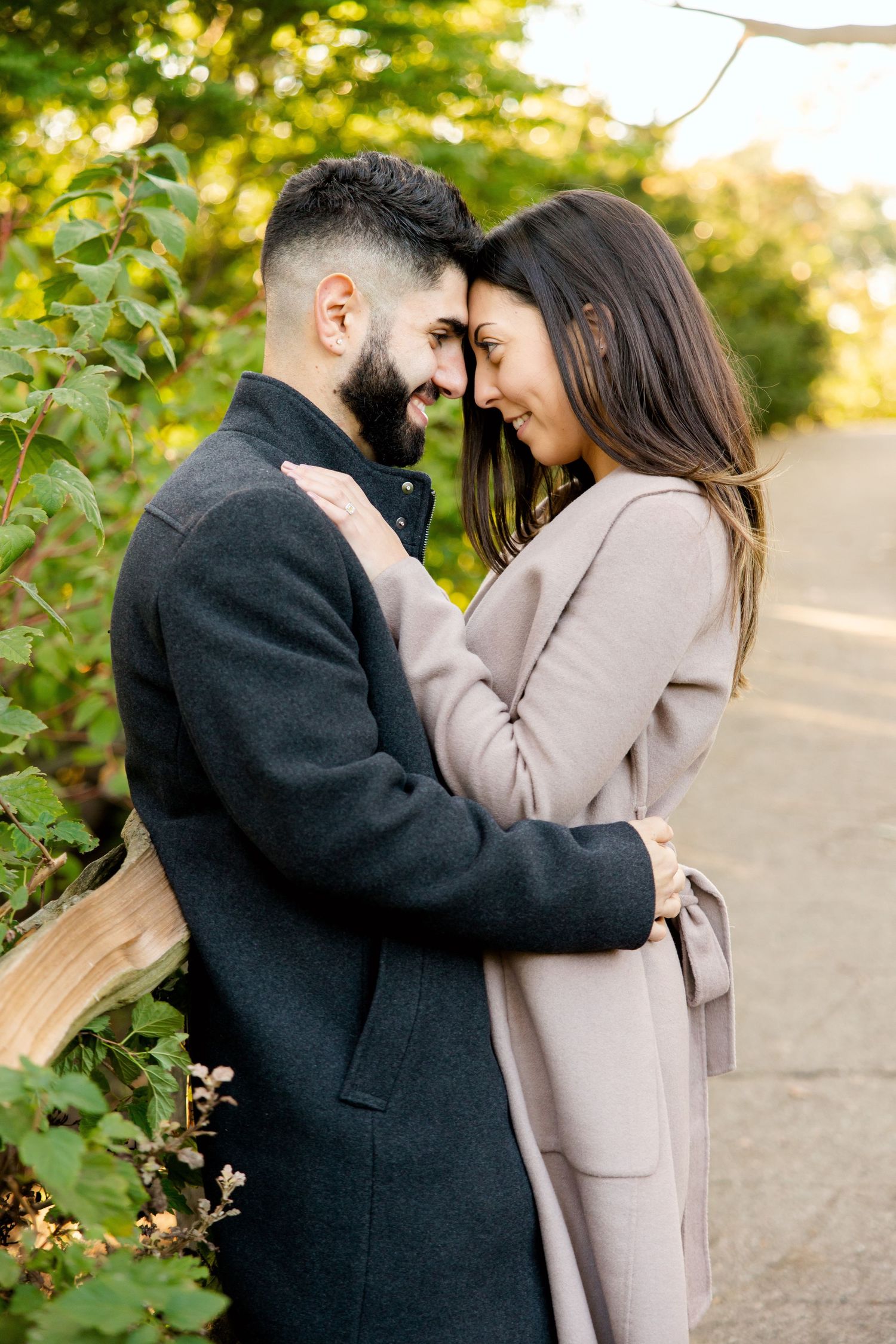 Couple in warm coats sharing a tender moment on a garden path.