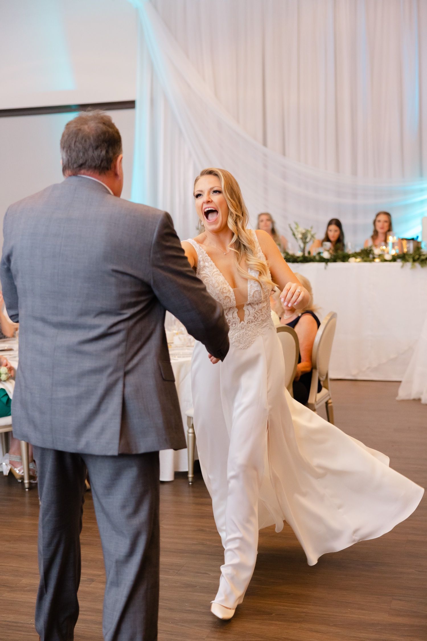 Joyful dance moment during wedding reception on hardwood dance floor.