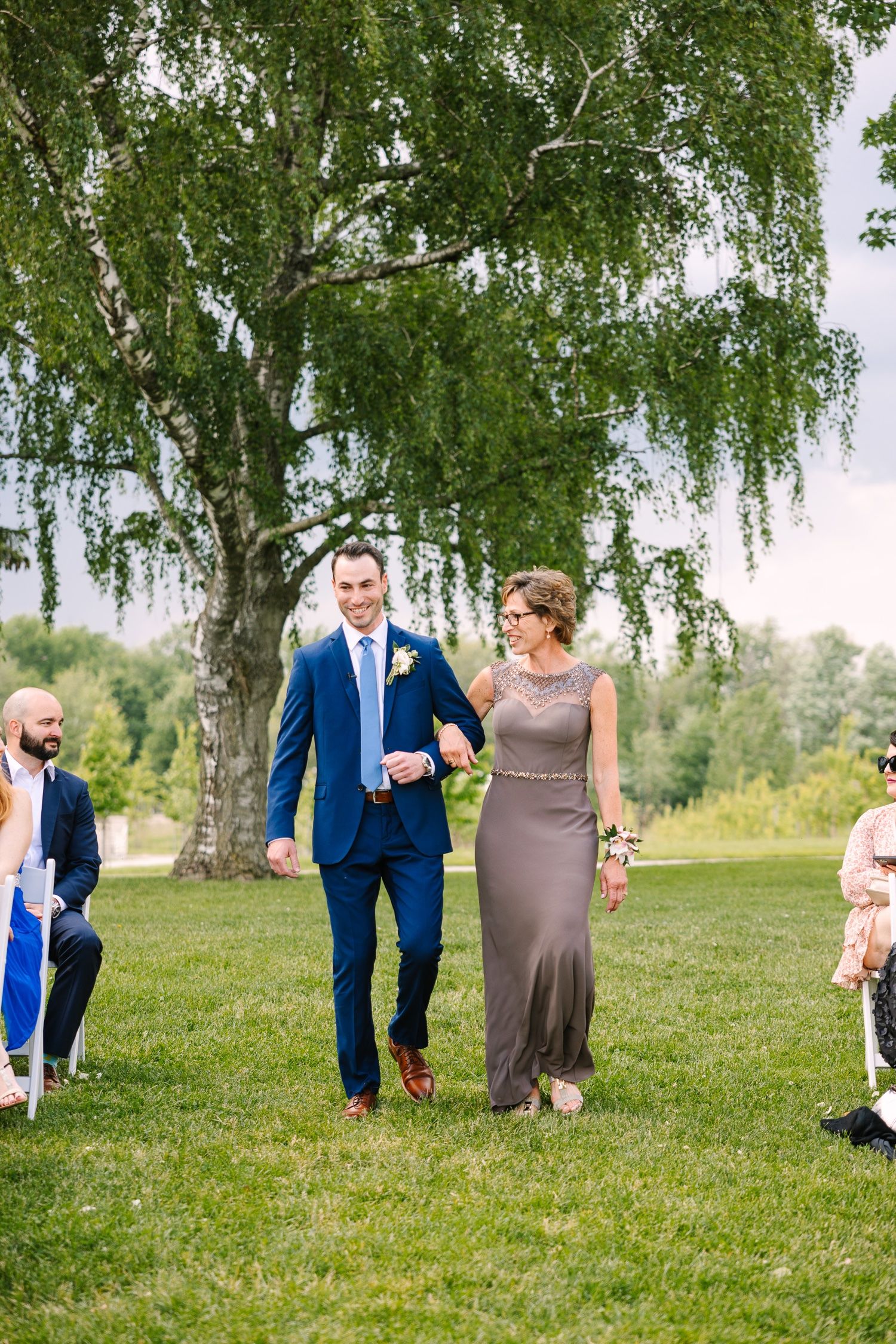 Formal processional walk down aisle during outdoor garden wedding ceremony.