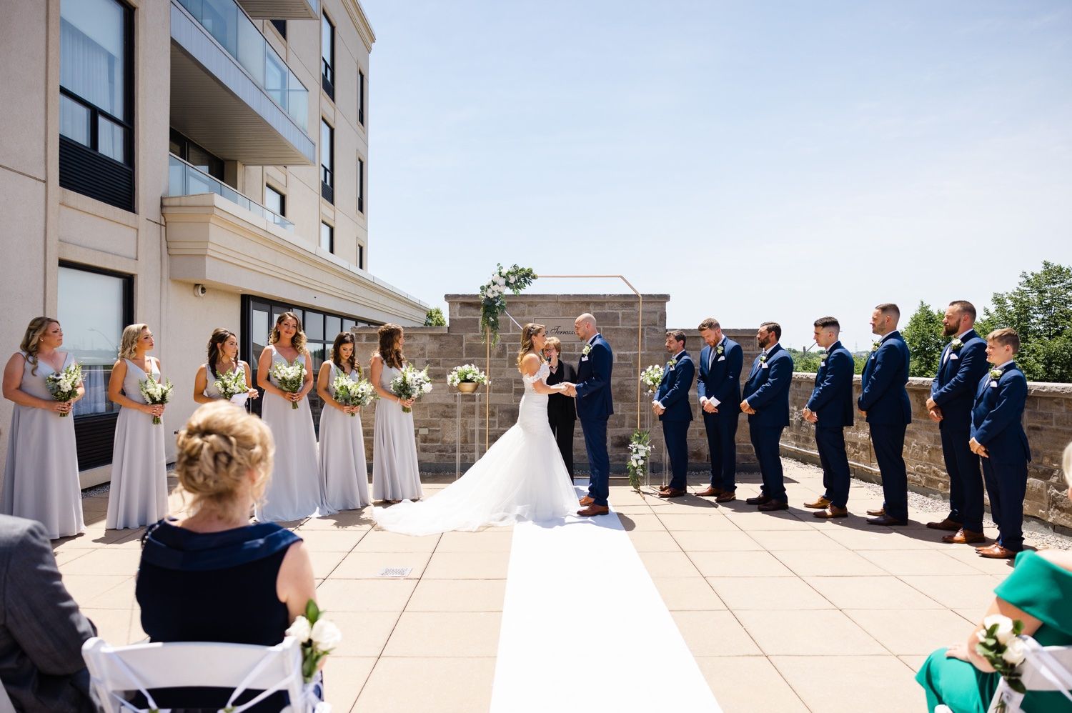 Wedding ceremony setup on rooftop patio with wedding party lined up and guests seated.
