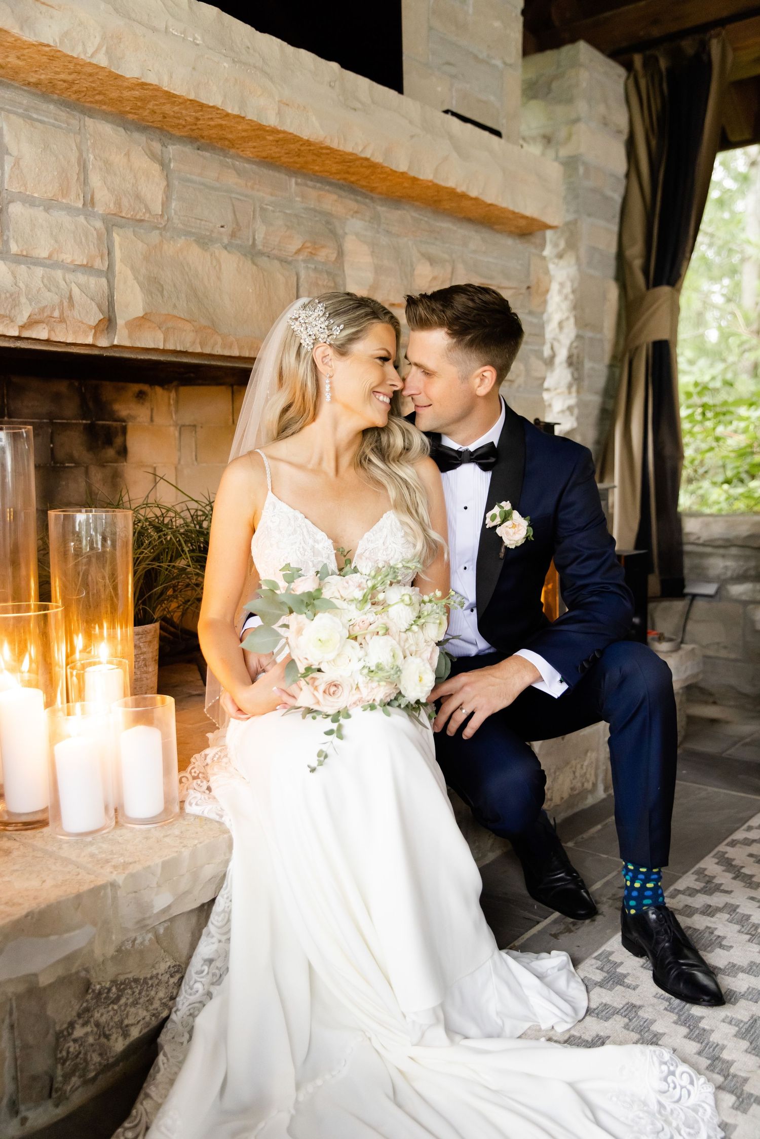 Romantic wedding portrait beside stone fireplace with candlelight.