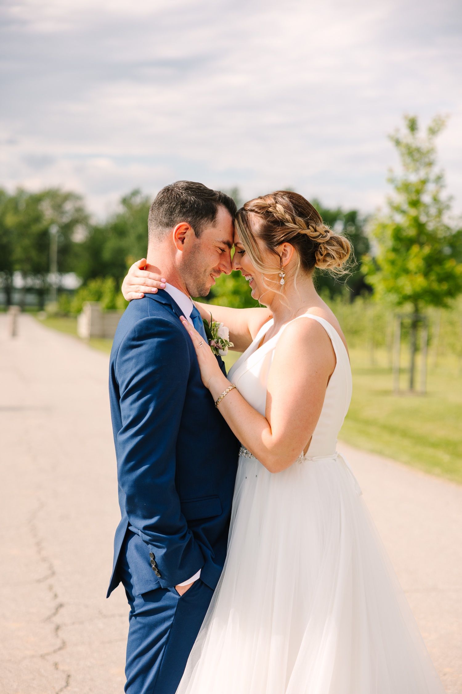 Intimate wedding moment captured on sunlit path with romantic lighting.