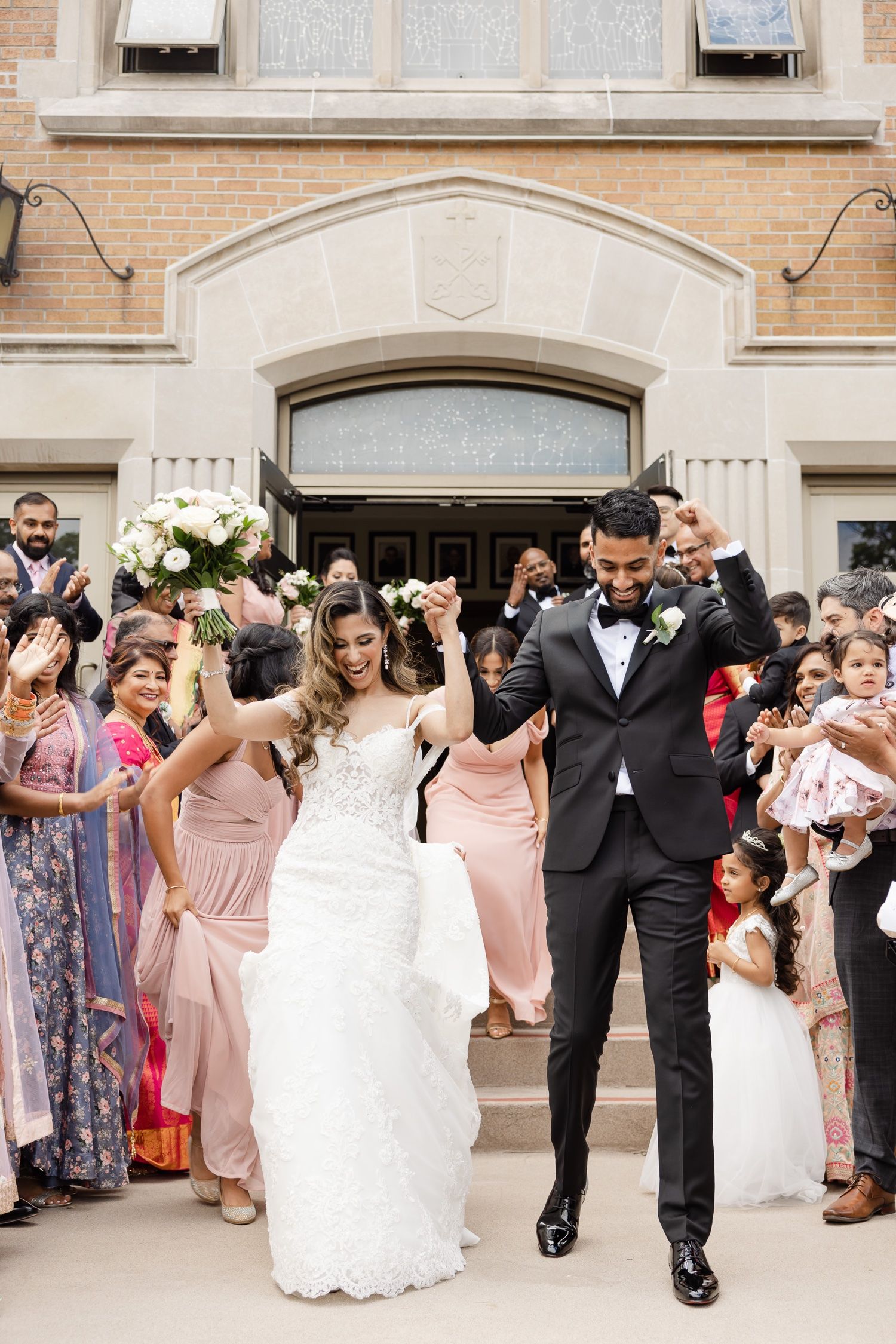 Celebratory exit from church with guests cheering on steps.