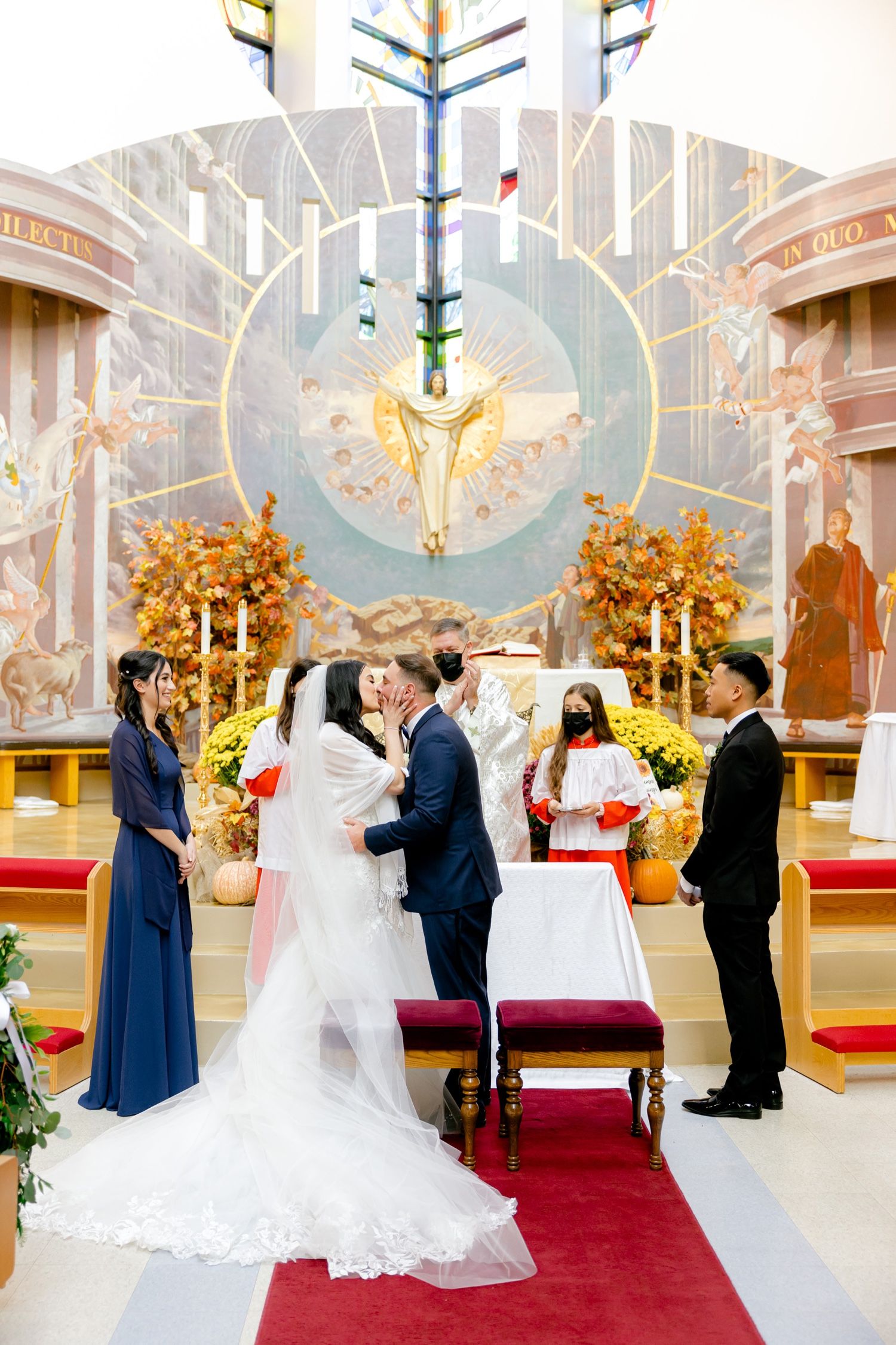 Wedding ceremony taking place under a dramatic circular stained glass window with golden decorations.