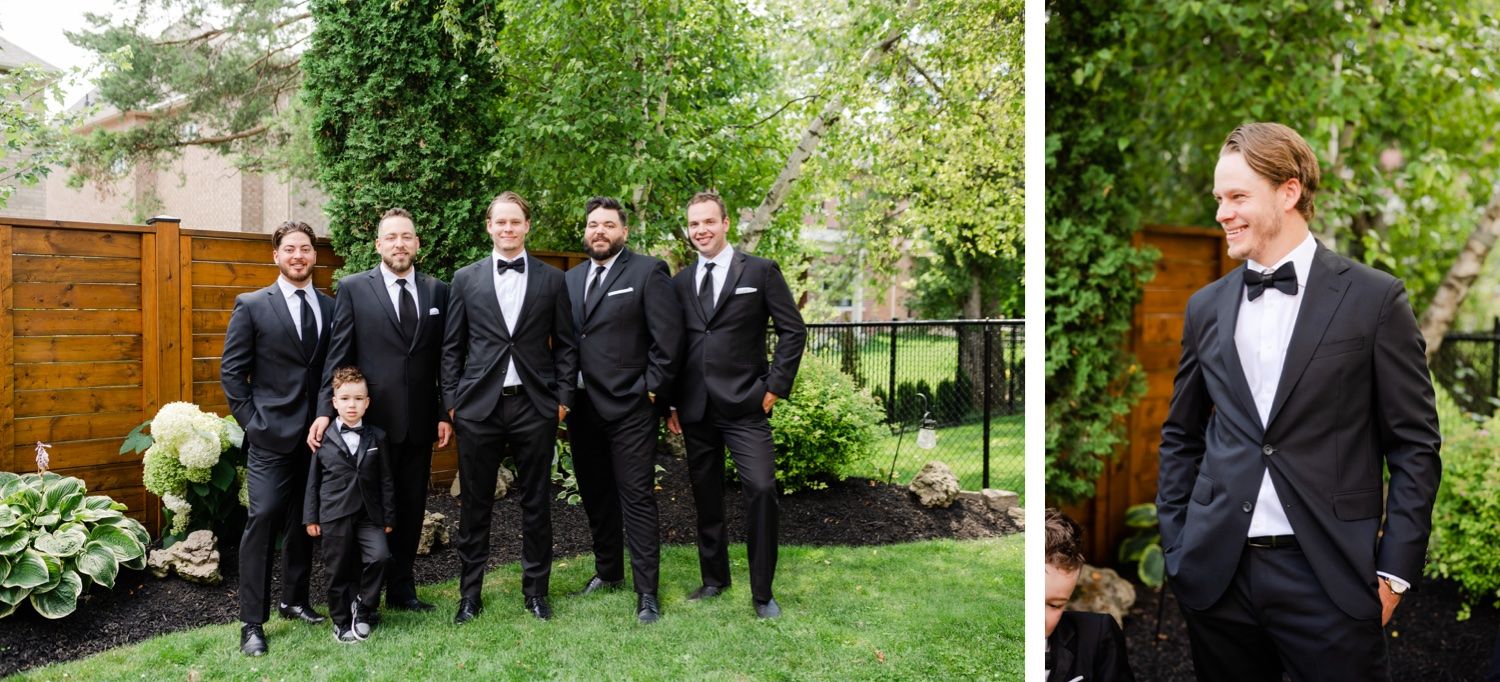 Wedding party in black tuxedos posing in a garden setting.