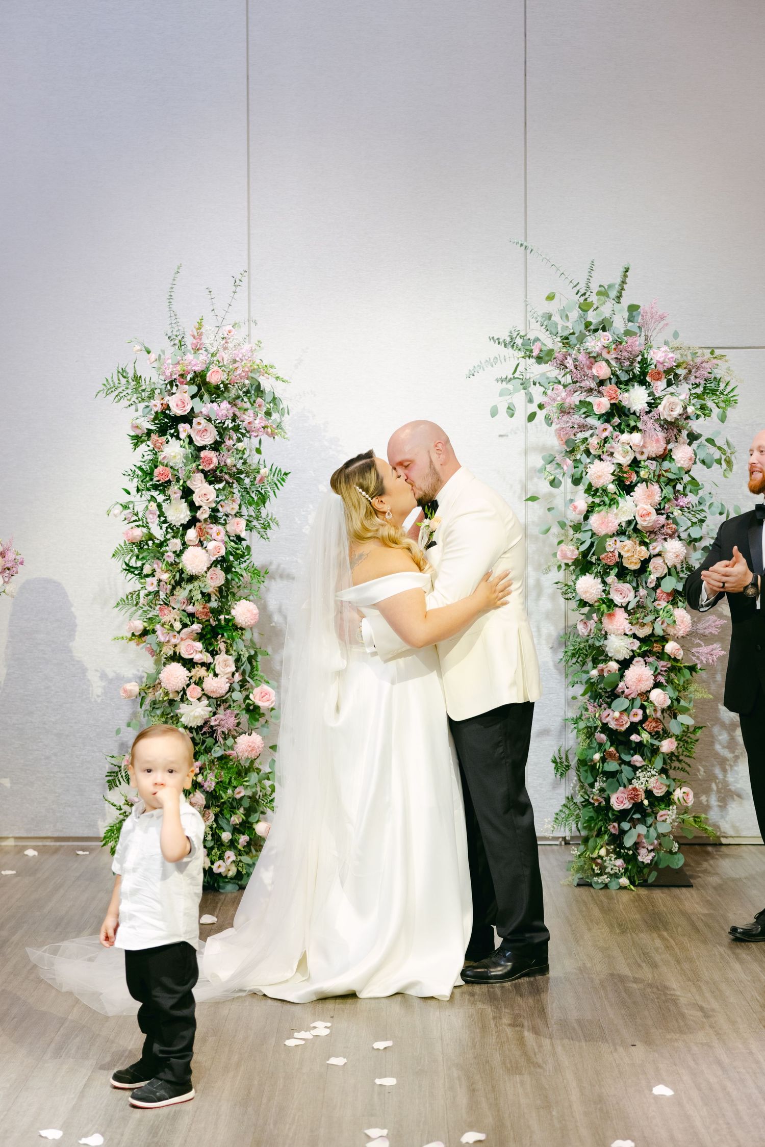 Sweet wedding moment with young child watching couple share their first kiss.