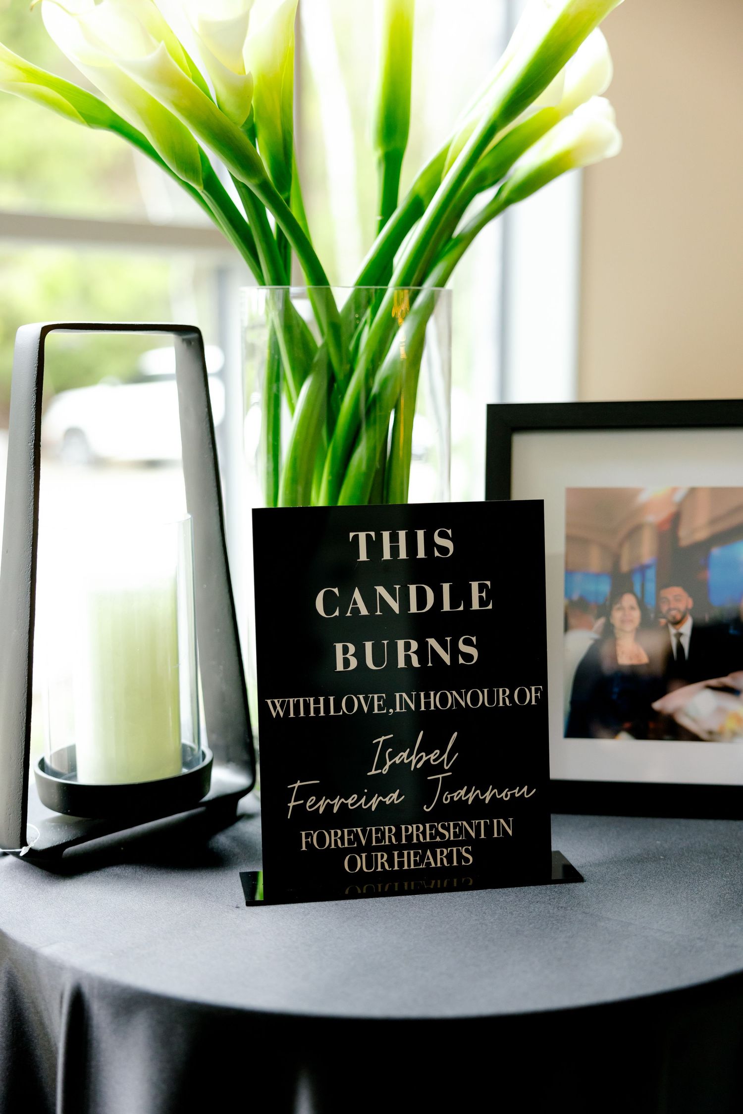 Memorial candle display with white calla lilies and touching tribute message.