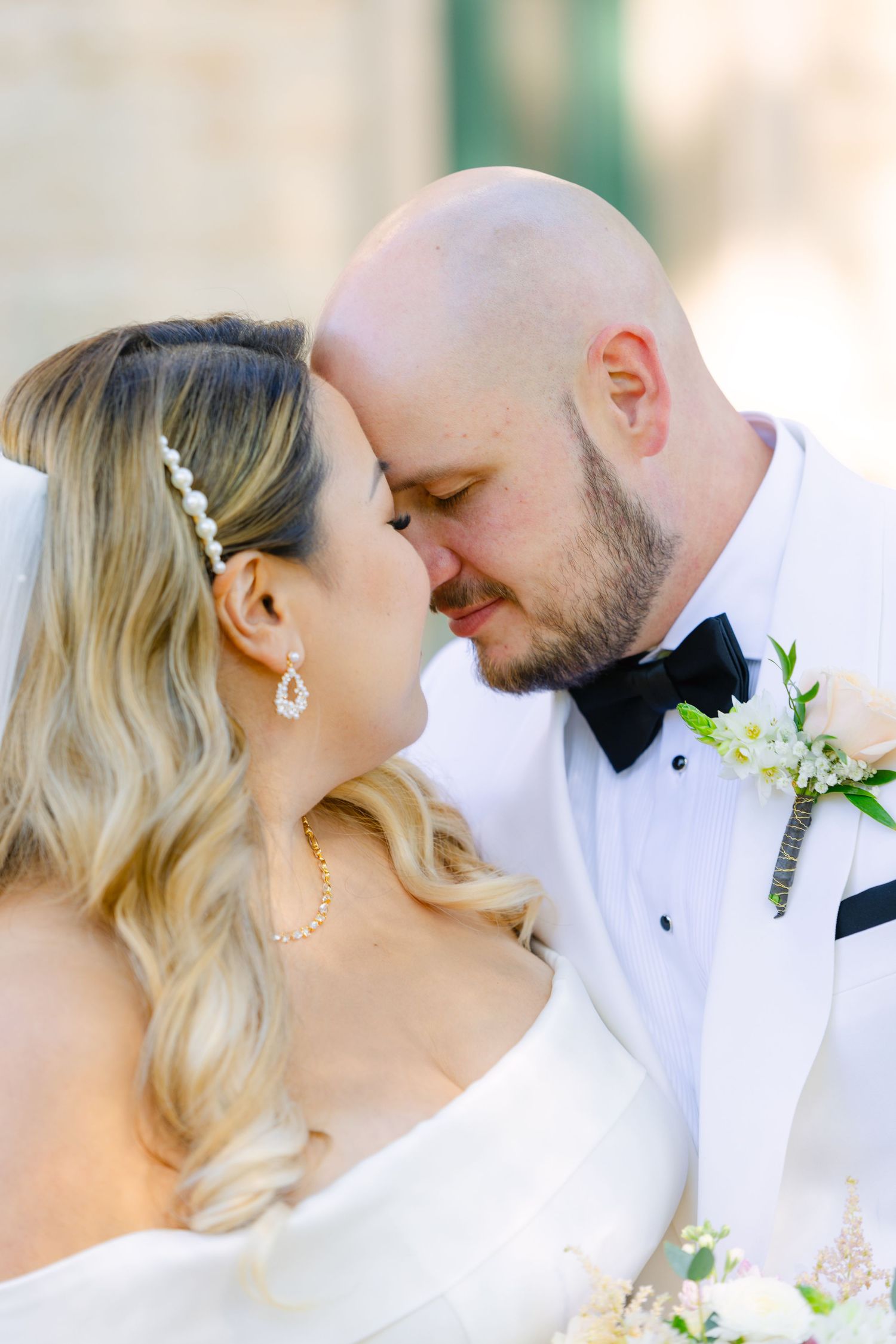 A romantic wedding portrait shows a tender moment between newlyweds as they share an intimate embrace outdoors.