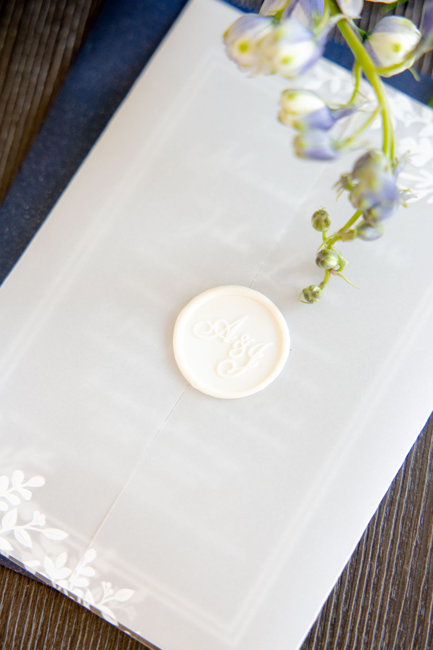 White wax seal on elegant envelope with delicate flowers in background.