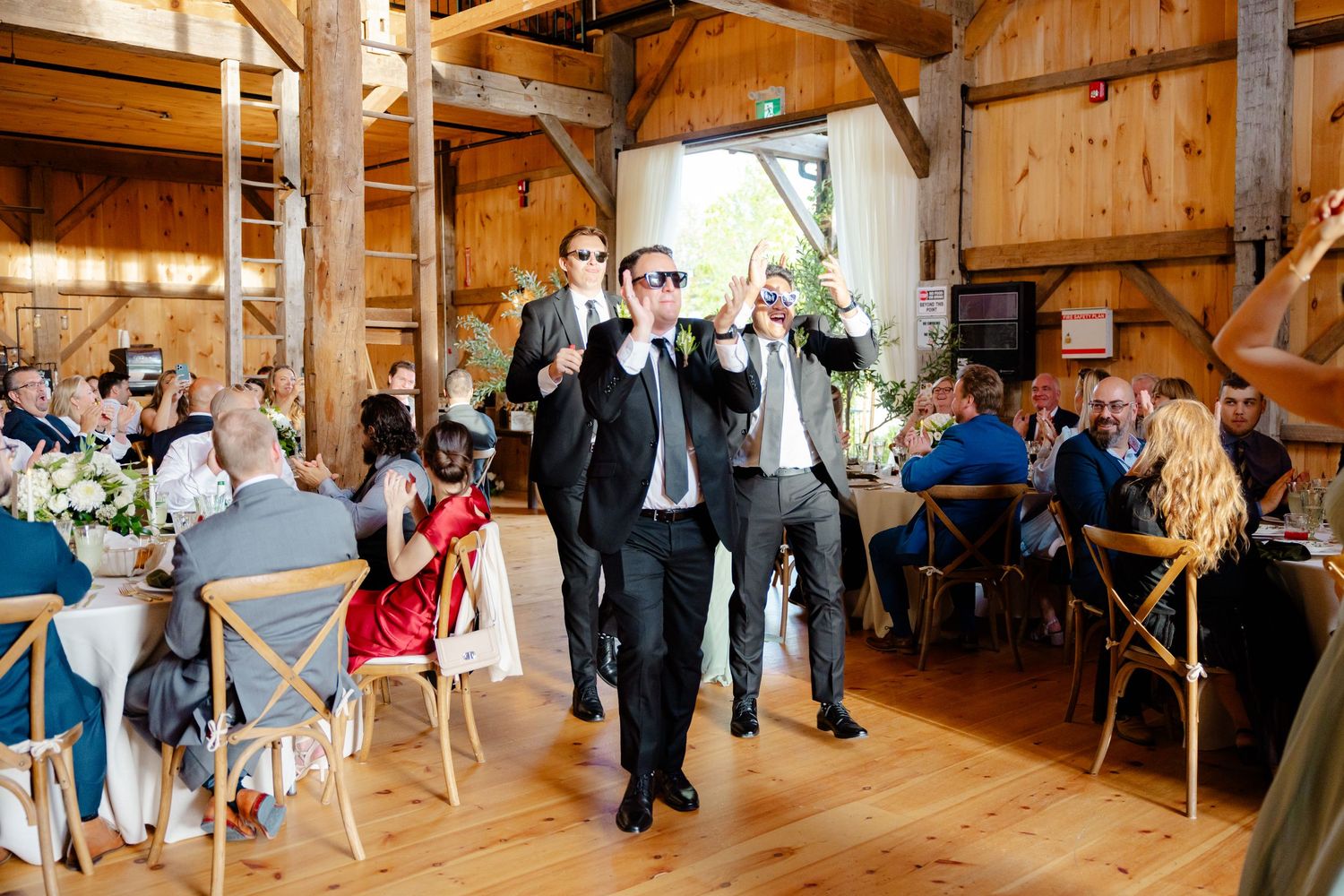 Wedding guests dance and celebrate in a rustic barn reception venue.