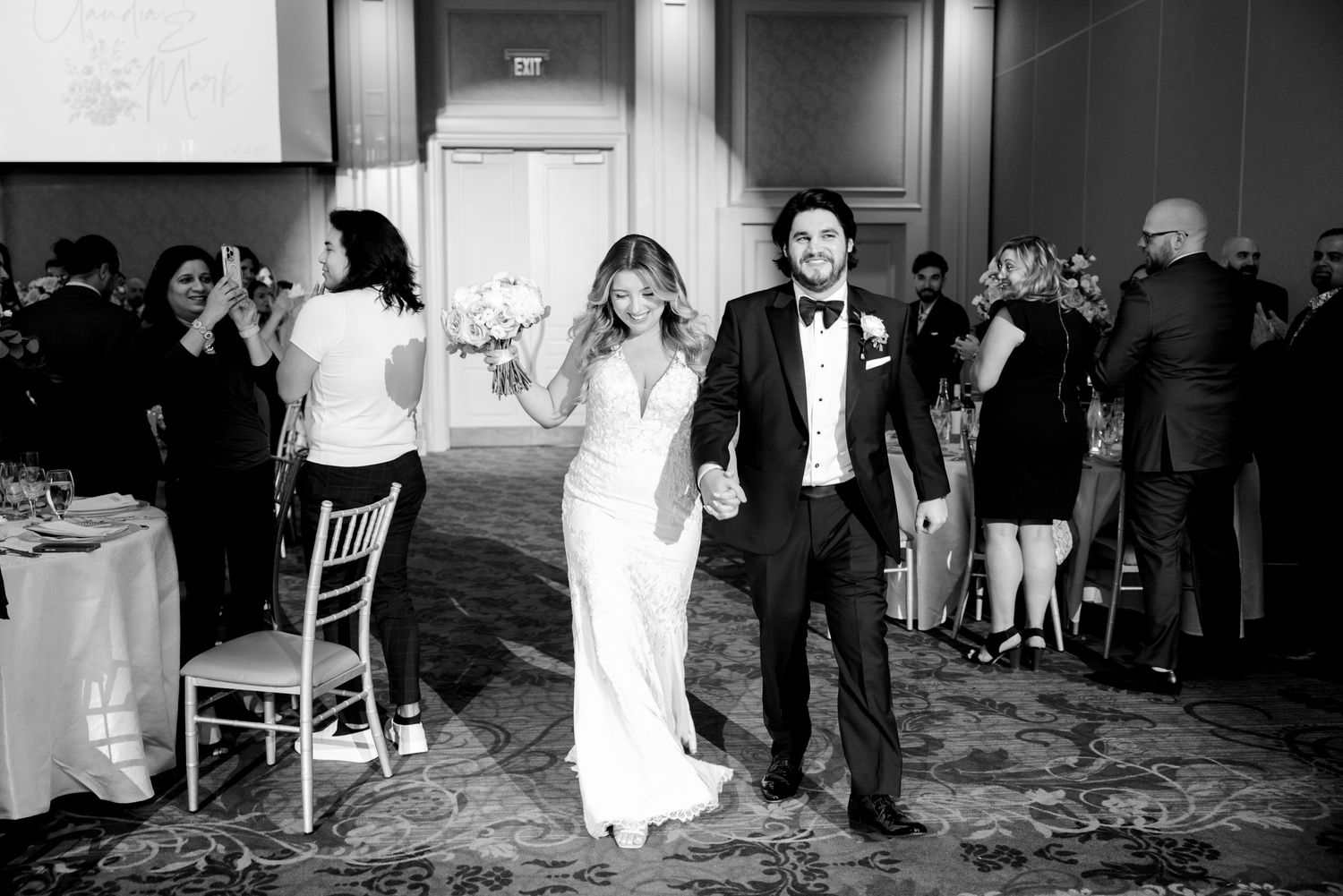 Wedding couple celebrates during reception entrance while guests watch.