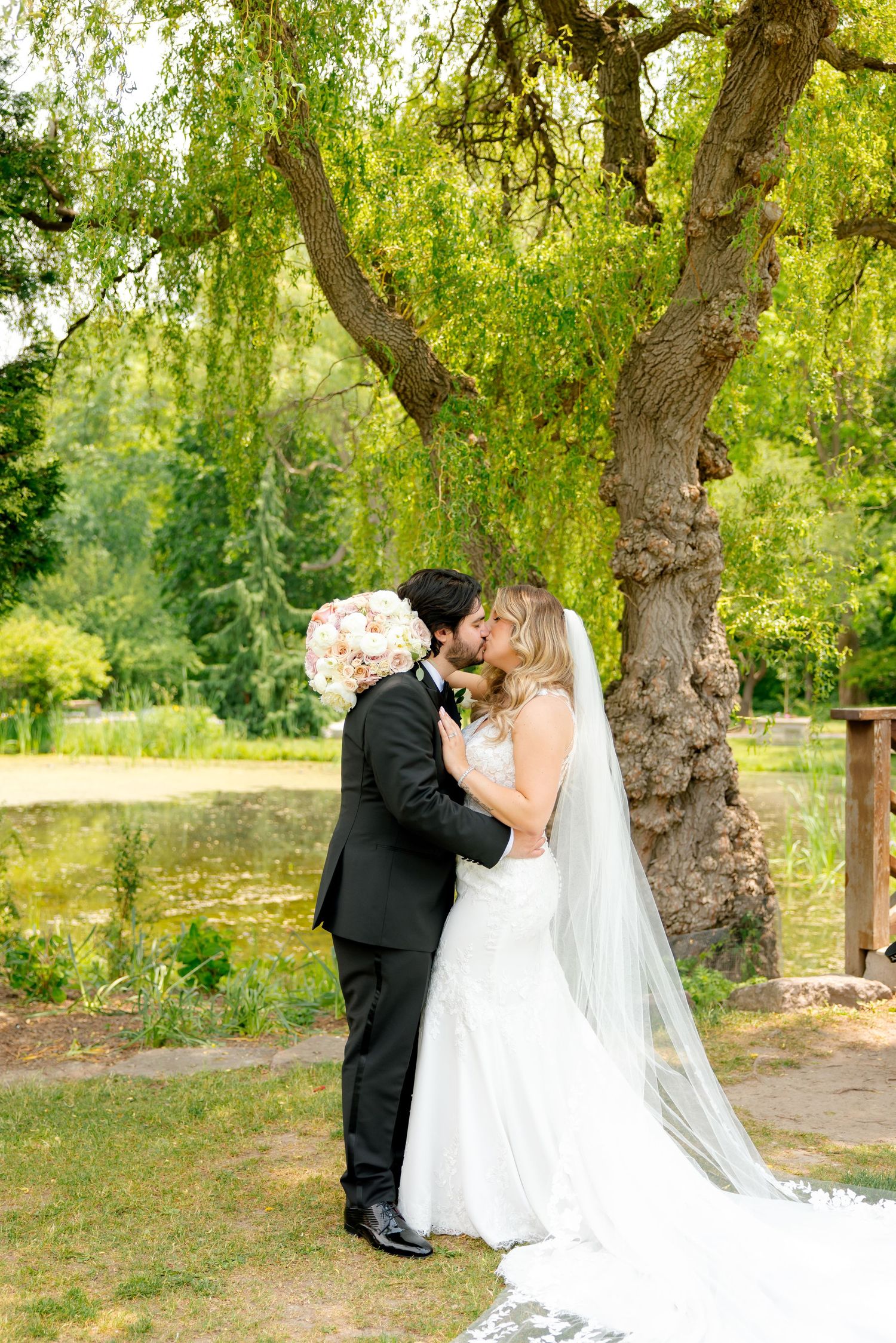 Elegant wedding couple sharing a tender moment beneath a weeping willow tree.