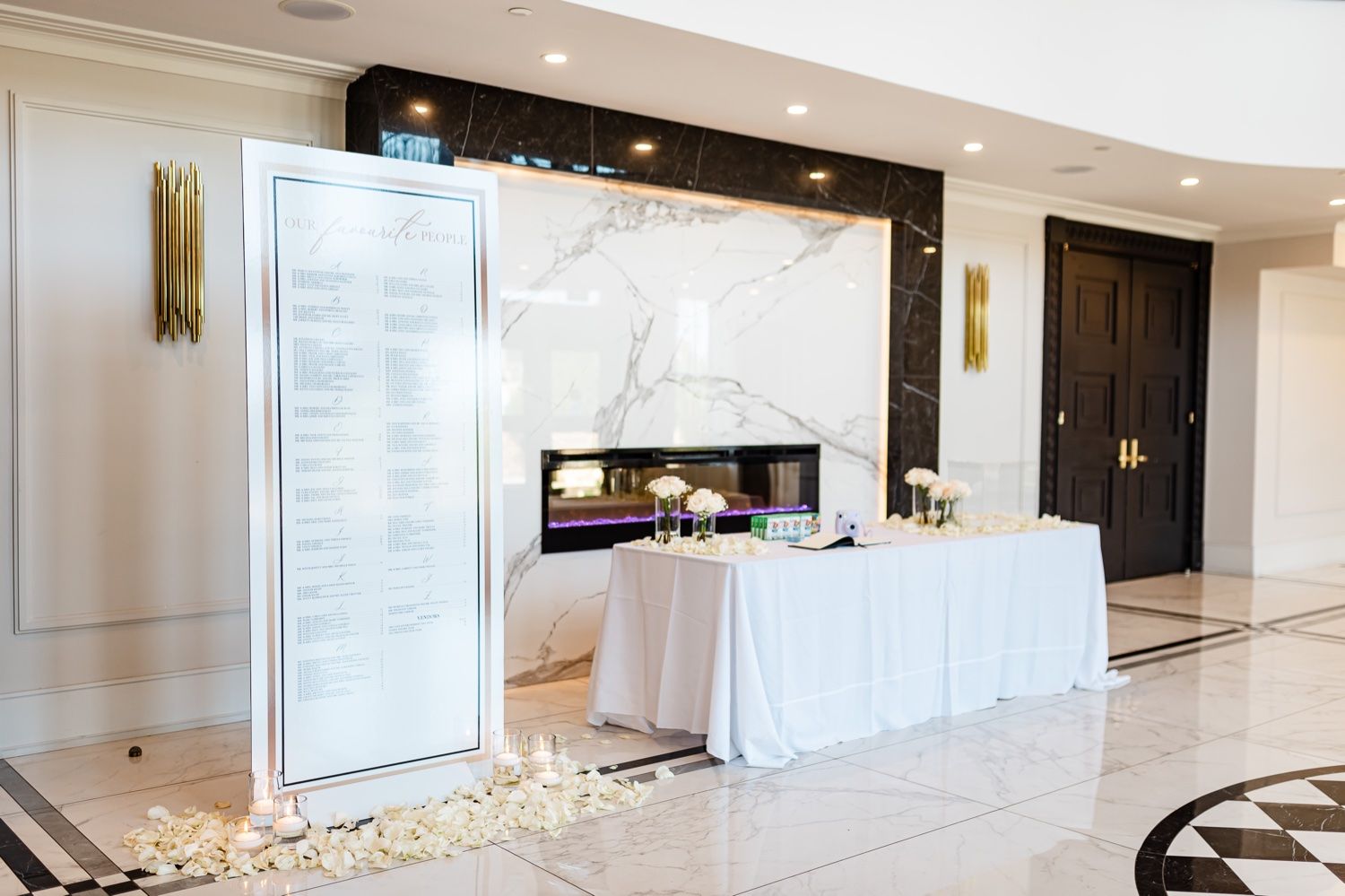 Modern wedding reception setup with white seating chart display and guest book table.