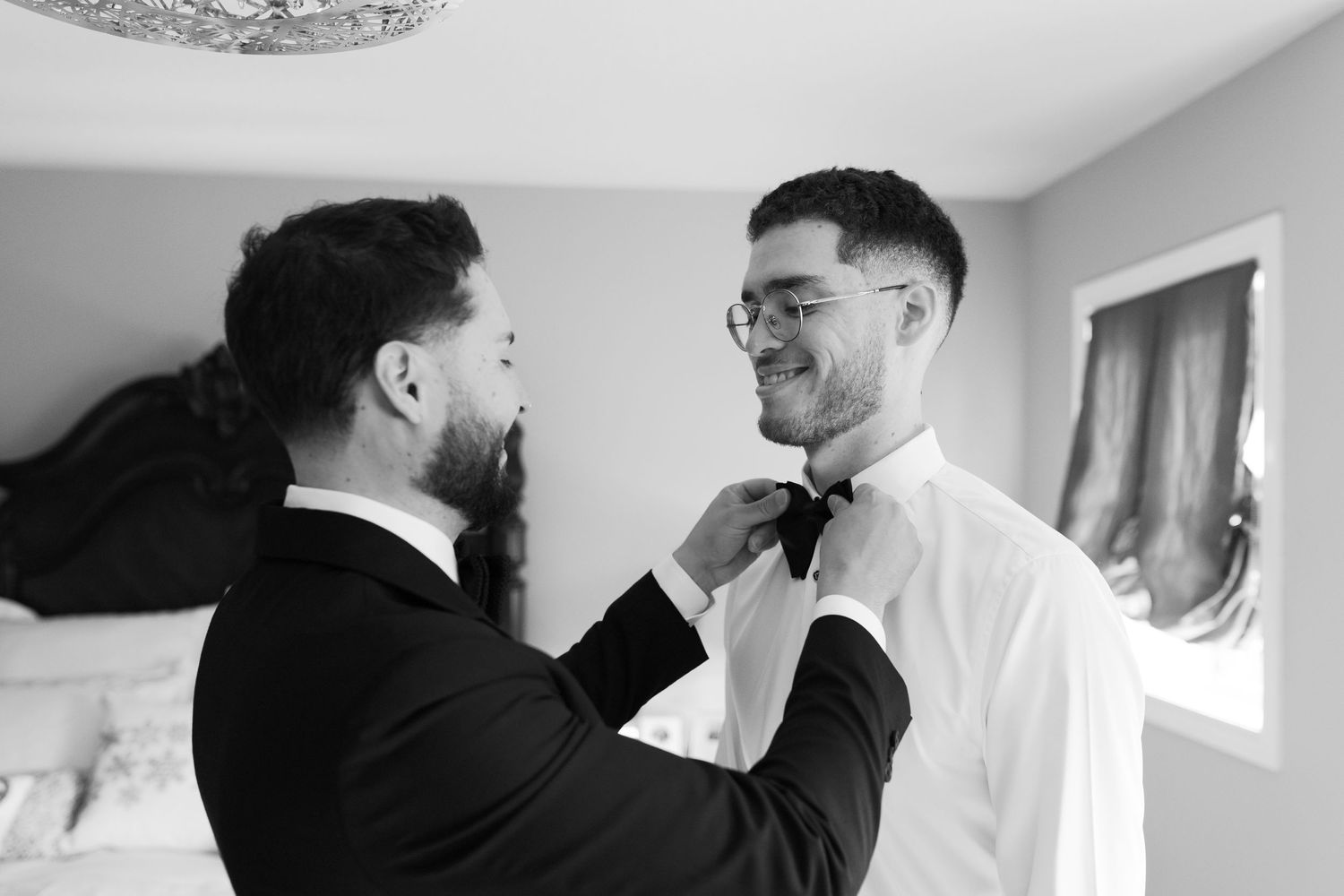 Black and white image of formal wear preparation with bowtie adjustment.