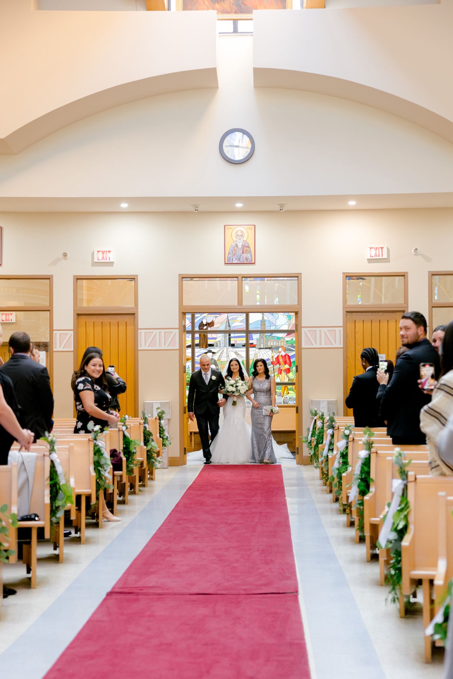 Church ceremony processional with red carpet aisle and decorated pews.