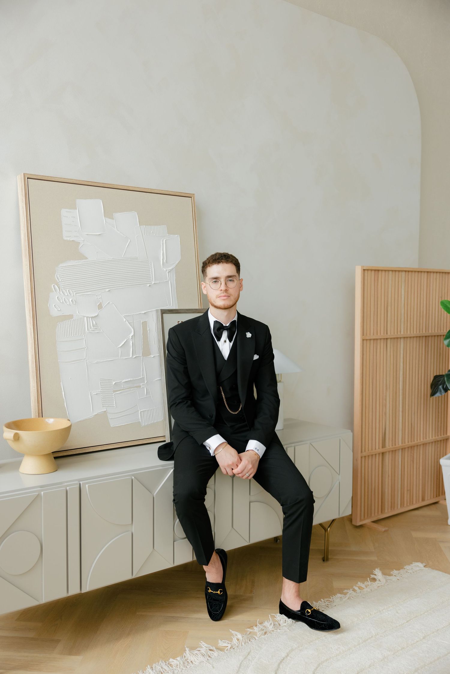 Classic black tuxedo with bow tie against minimalist white decor.