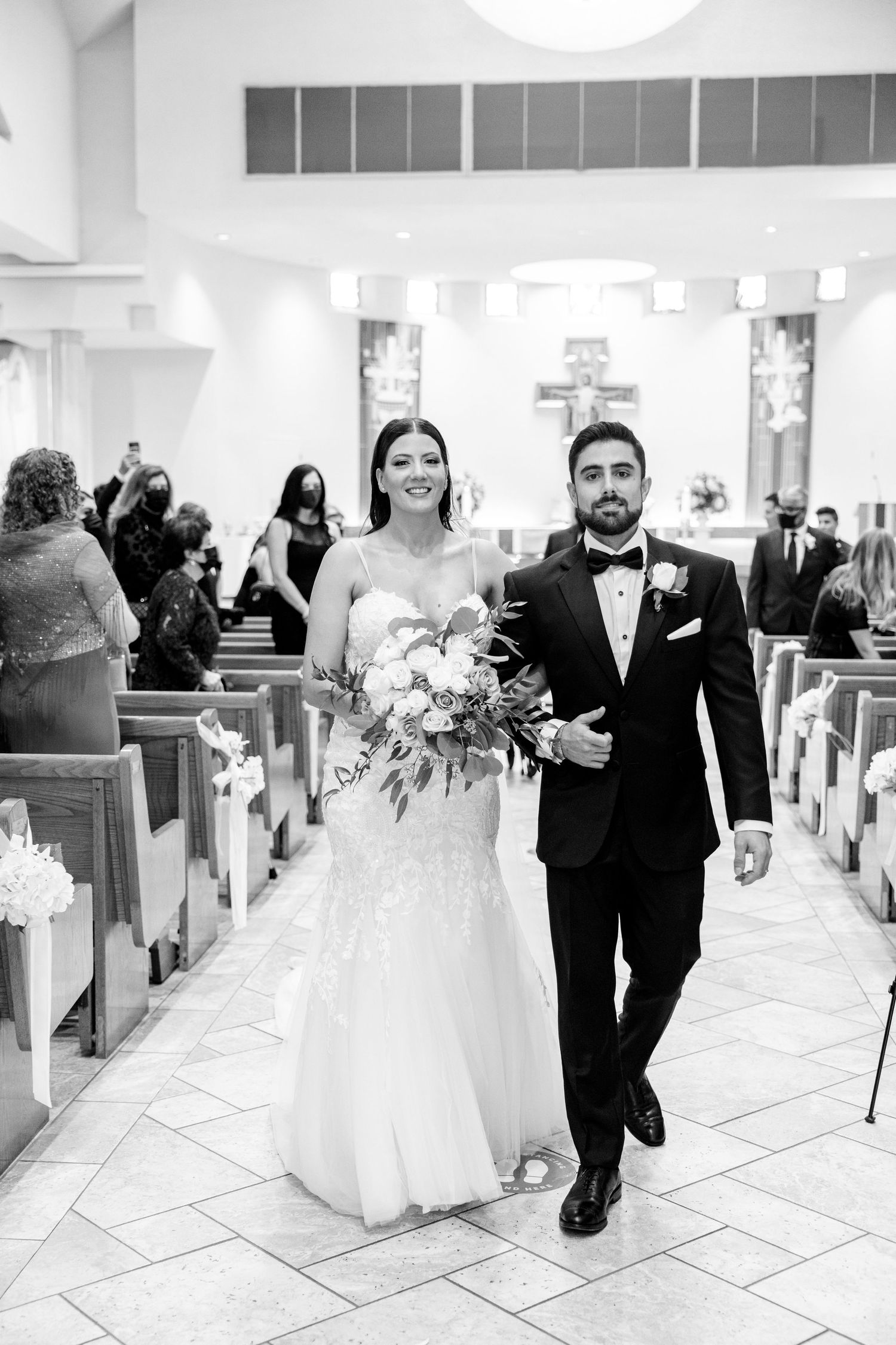 A cheerful couple walks down the church aisle together after their wedding ceremony.