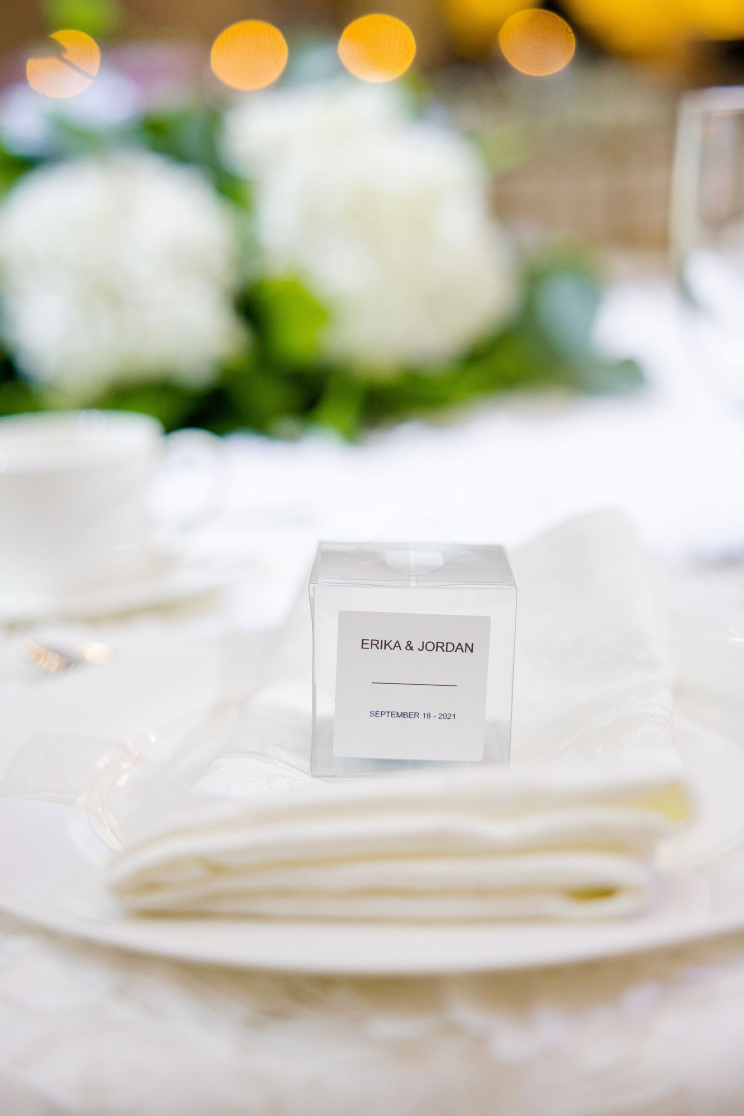 Close-up of wedding place card on white linen napkin with soft bokeh background.