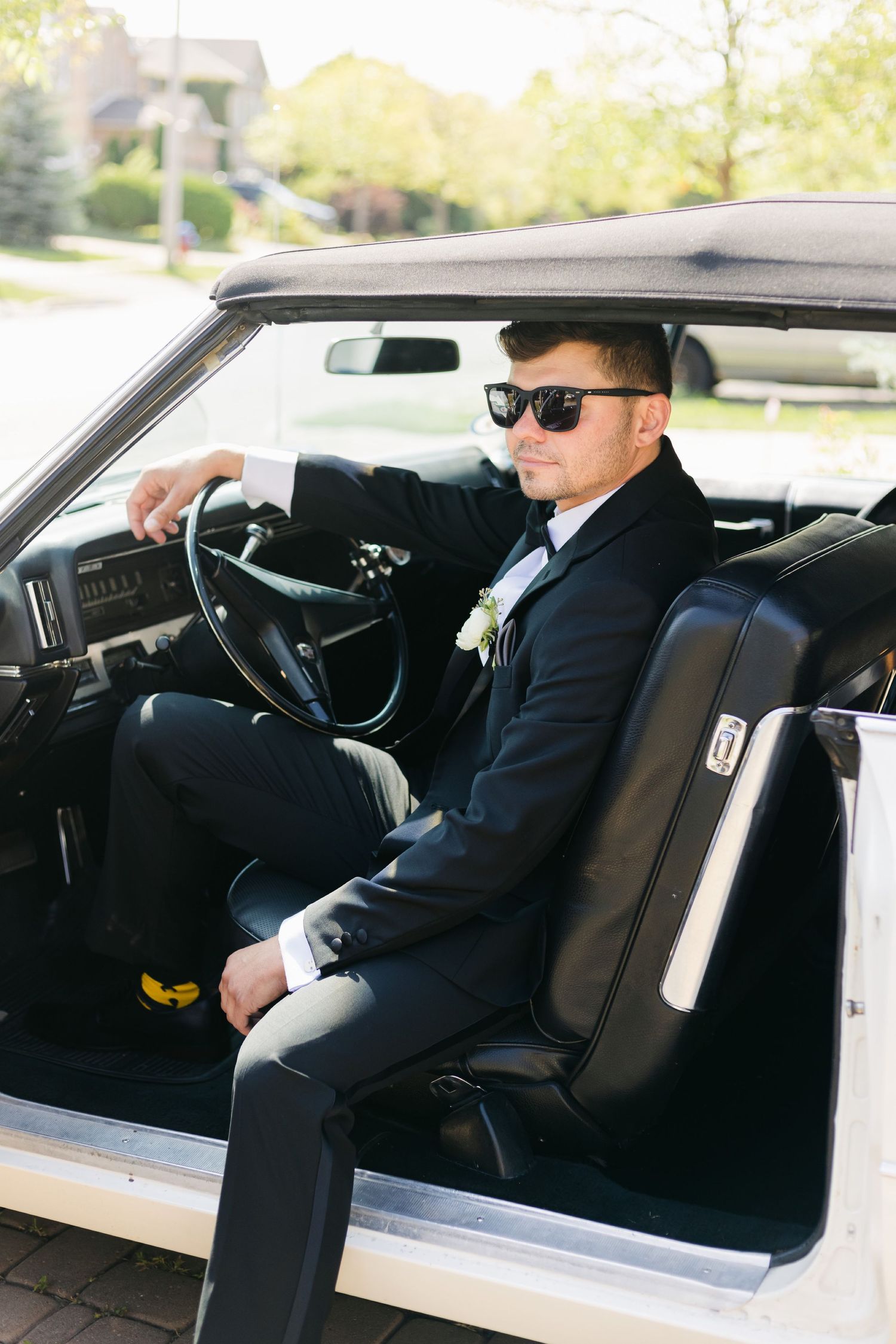 Classic car interior shot with formal attire and sunglasses creating retro aesthetic.