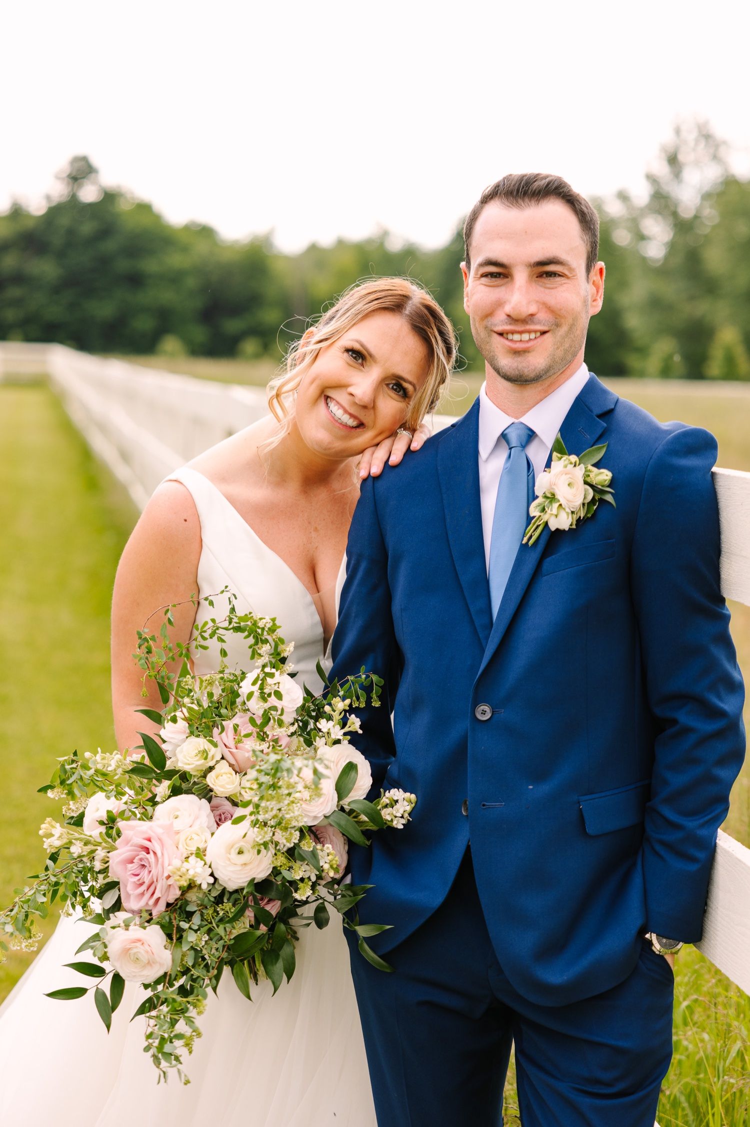 Elegant summer wedding portrait with beautiful bouquet and navy blue suit.
