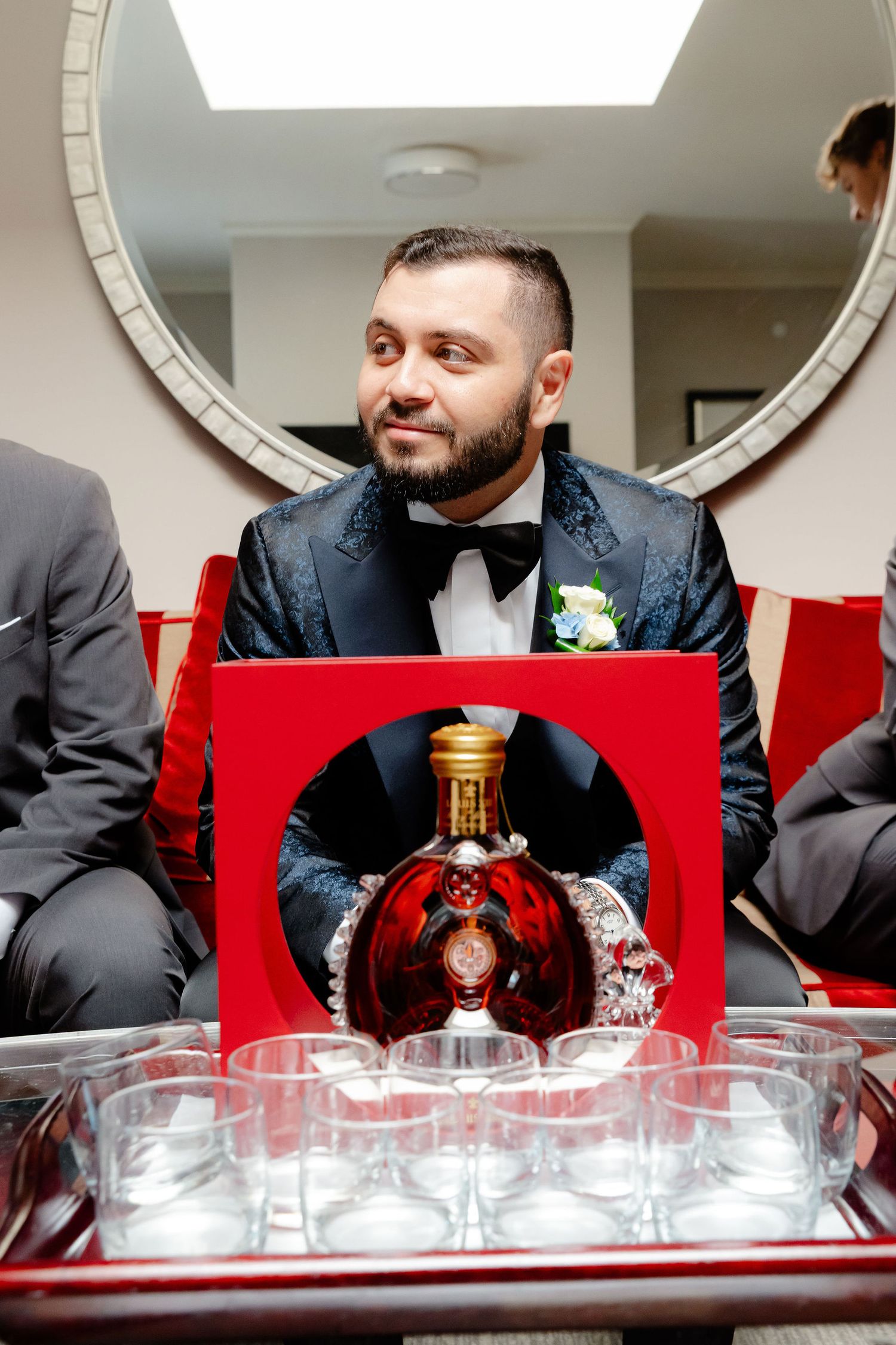 Formal event preparation scene with glassware and mirror reflections against a red accent wall.