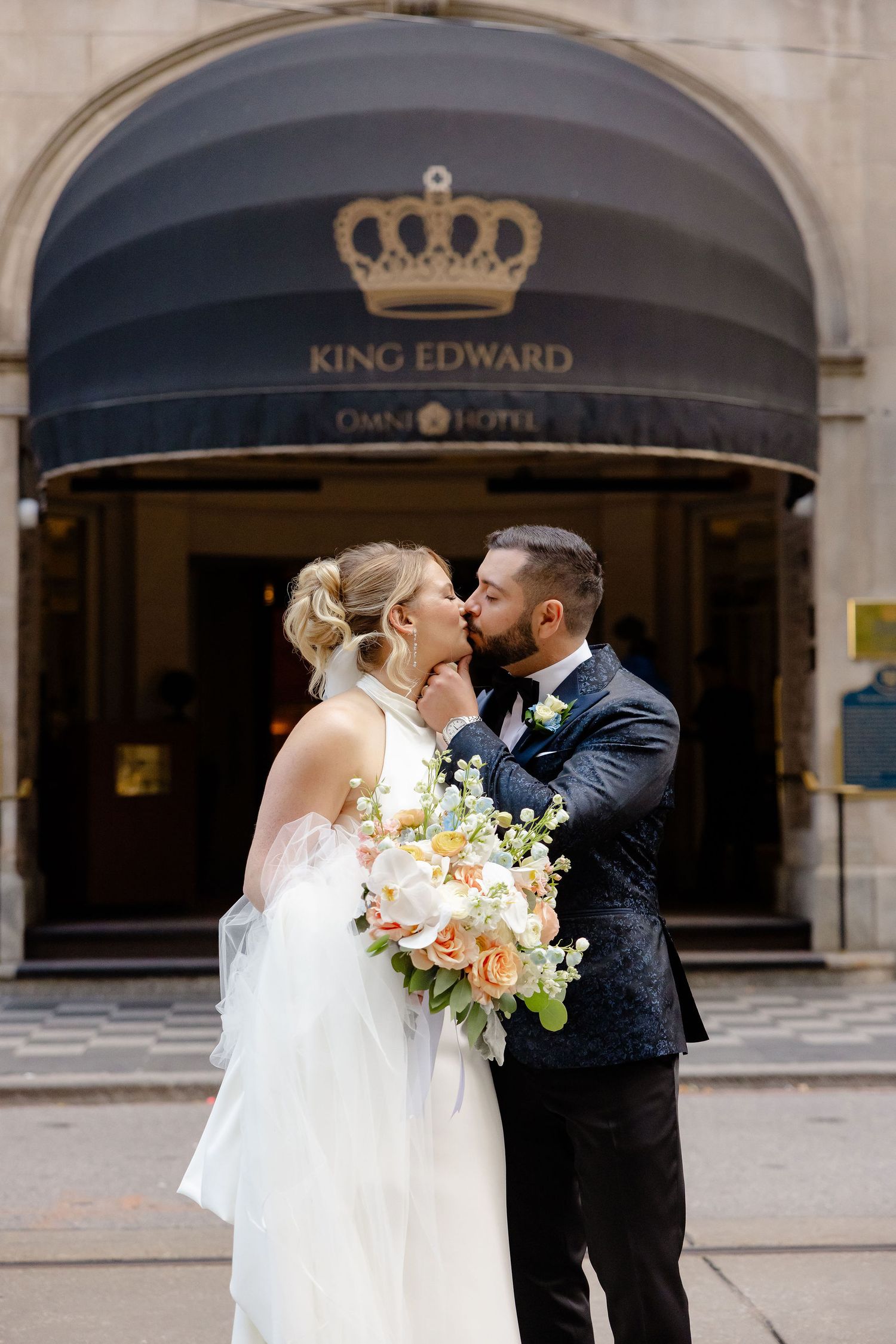 Romantic wedding portraits of couple embracing outside historic hotel entrance.