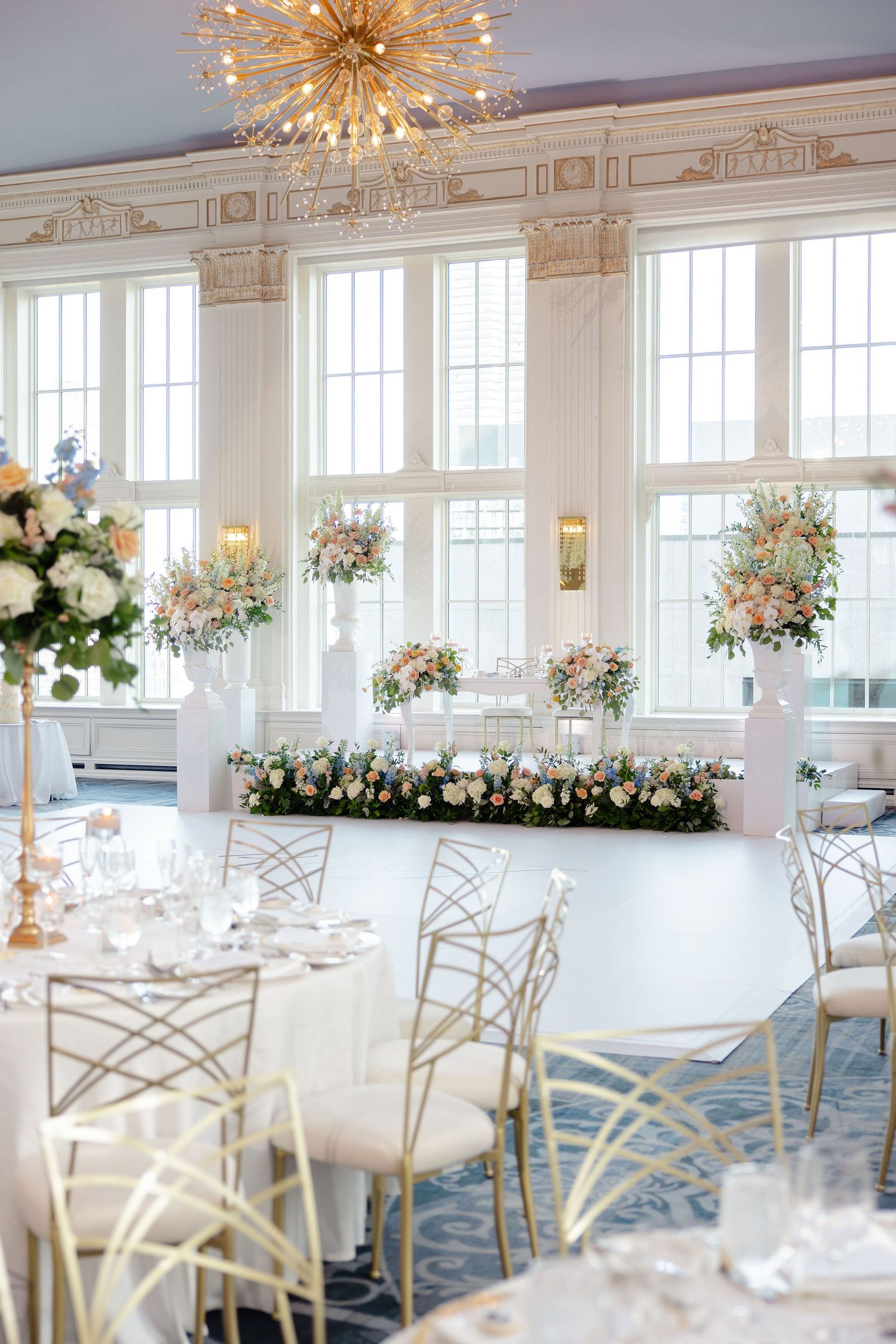 Wedding reception room with geometric chairs, round tables, and stunning floral centerpieces.