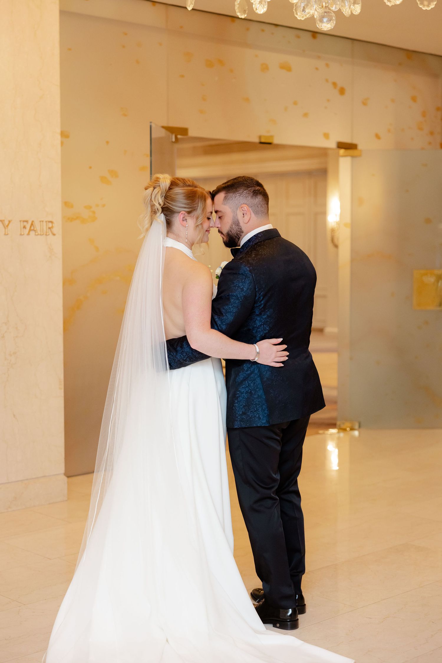 Wedding couple shares intimate first look moments in a warmly lit room with gold accents.