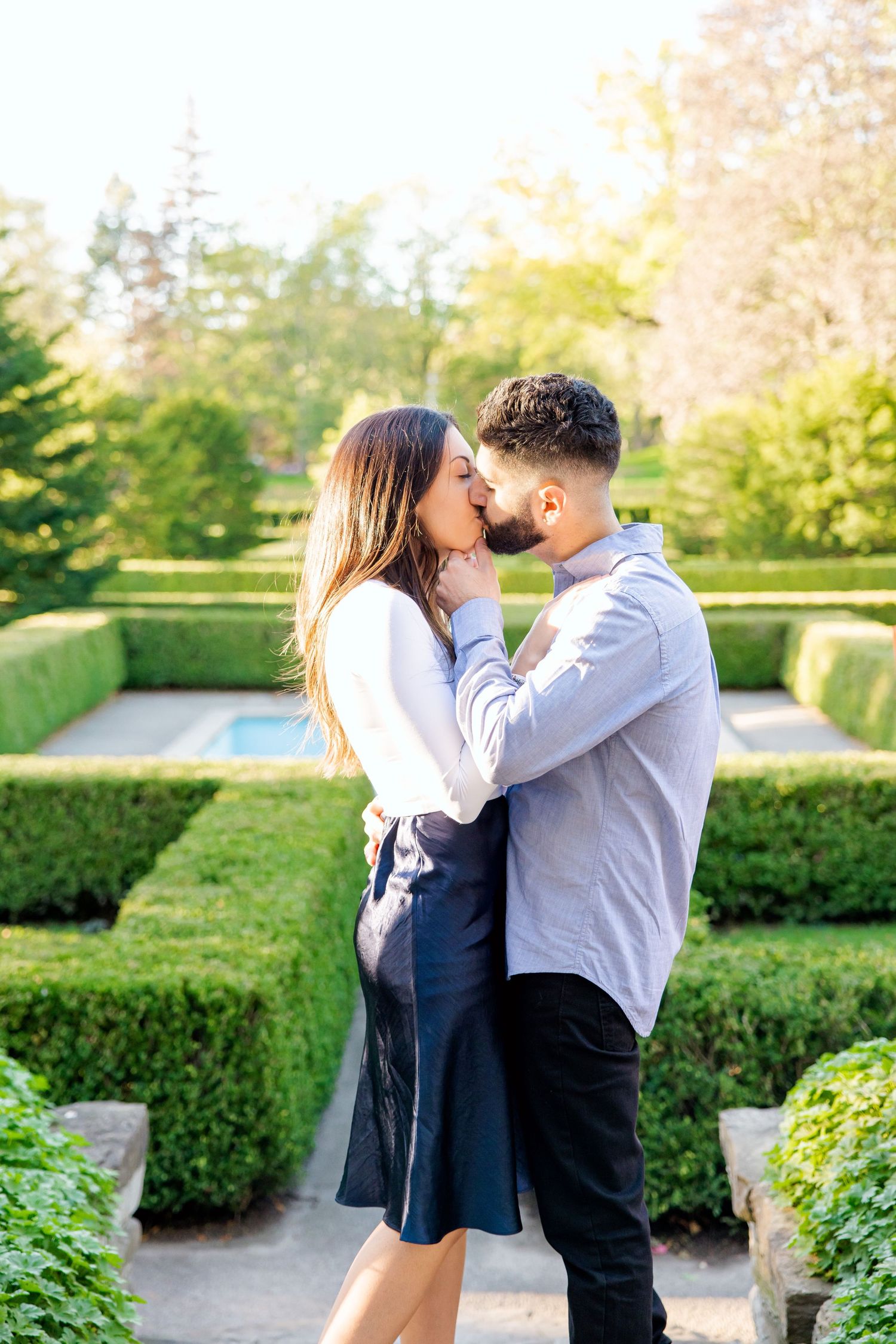 A romantic moment captured between a couple in a formal garden with perfectly trimmed hedges.