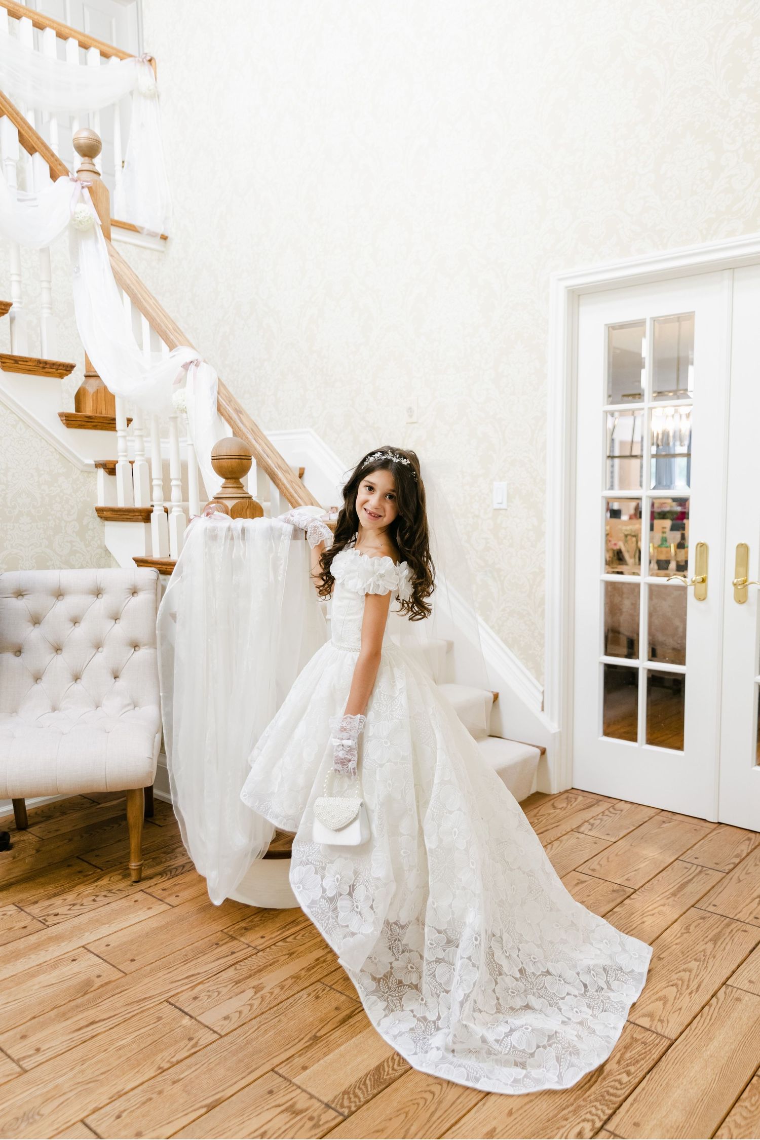 White baptismal gown with flowing train photographed near French doors.