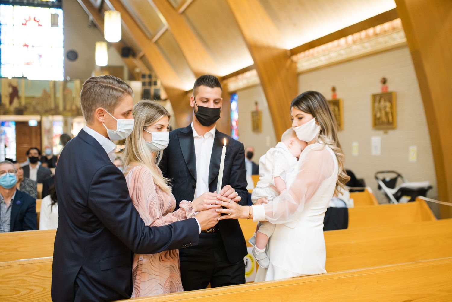 Masked attendees gather in church pews during baptism ceremony.