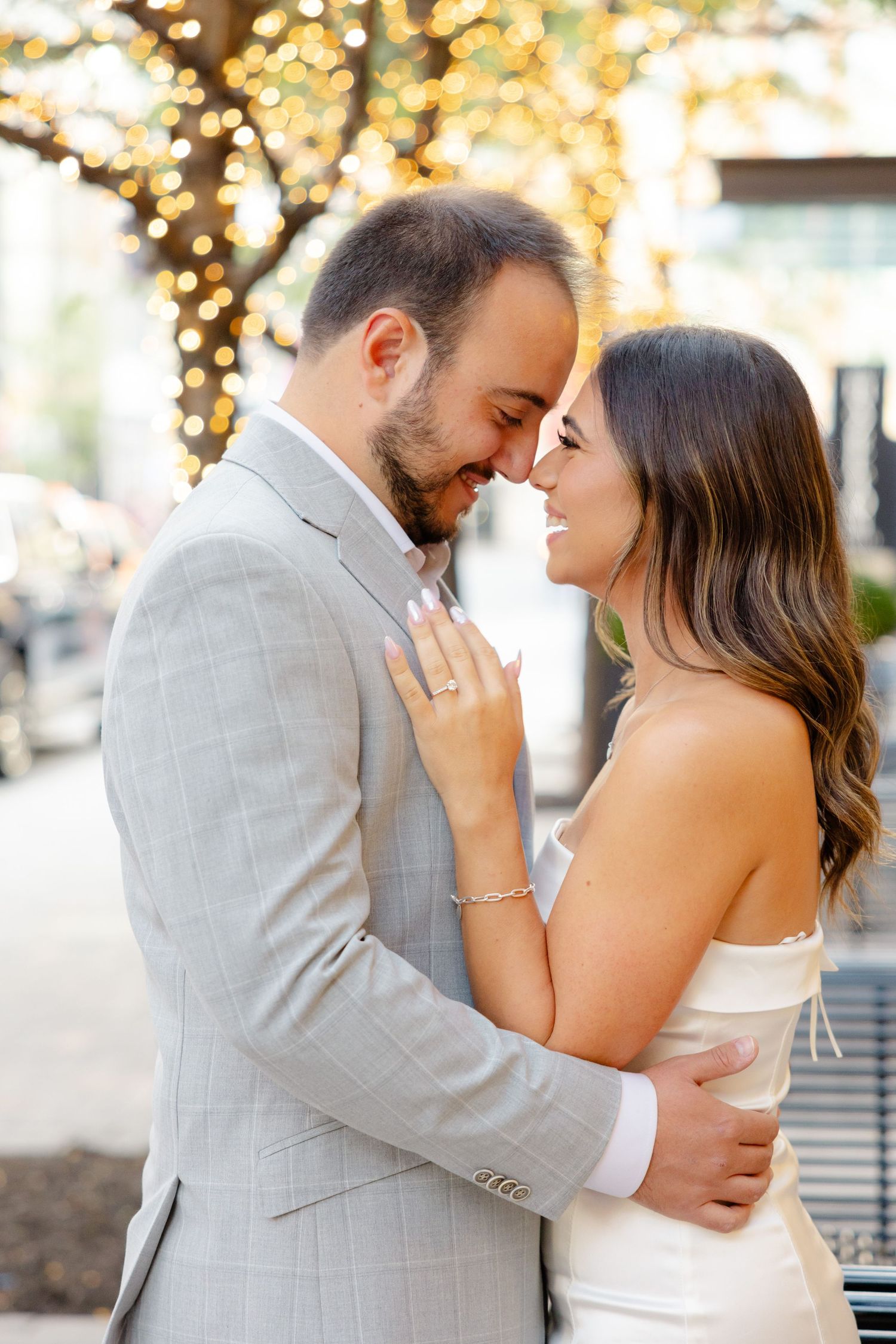 Intimate portrait of couple embracing with string lights creating warm ambiance.