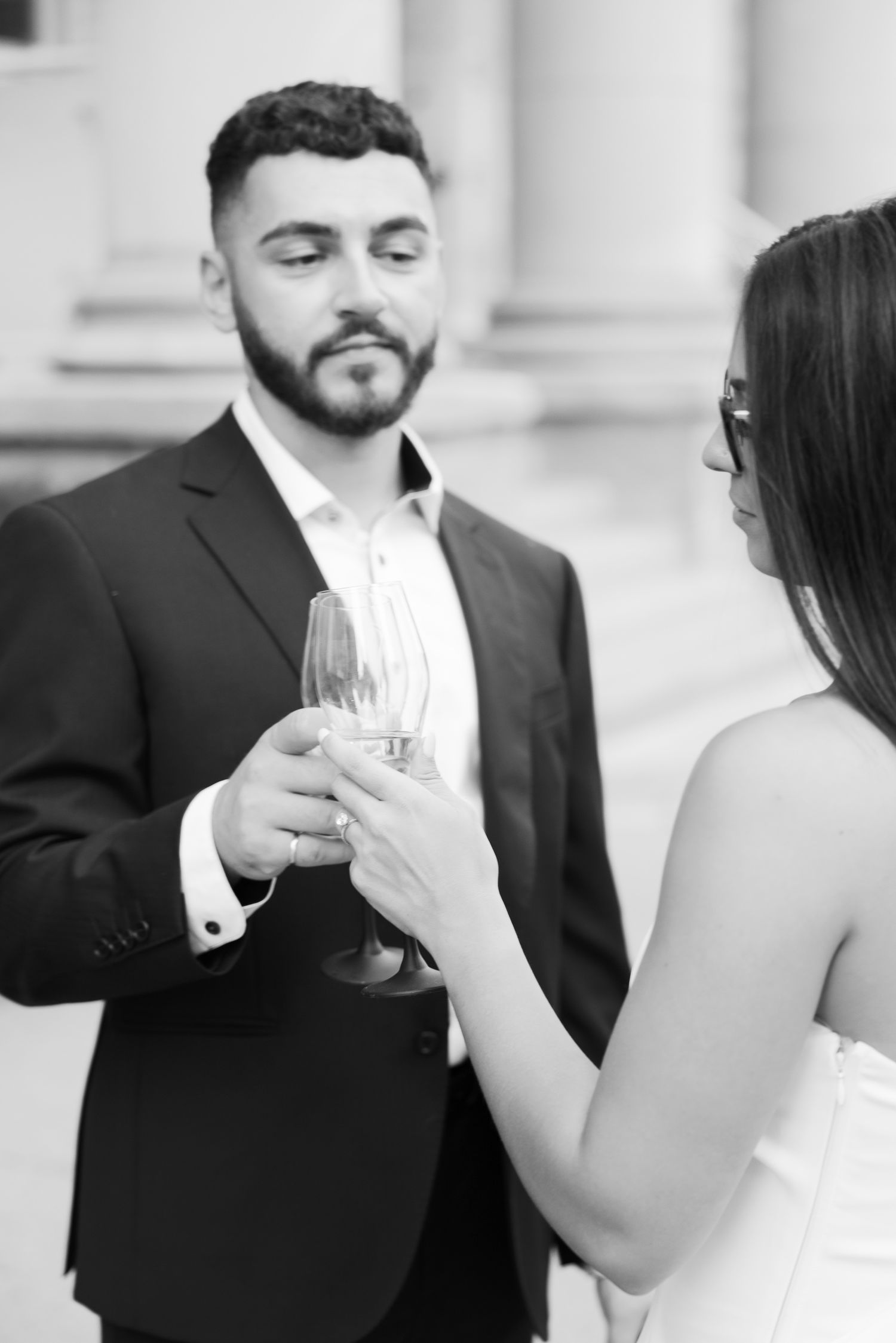Close-up shot of couple exchanging glances while holding wine glasses outdoors.