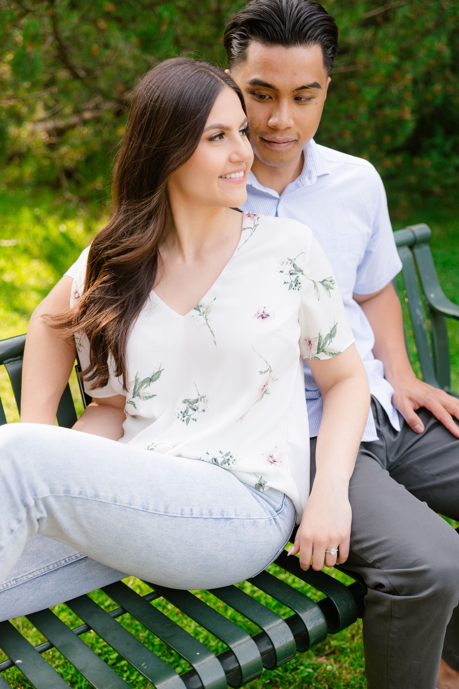 A couple shares an intimate moment while sitting close together on a garden bench.