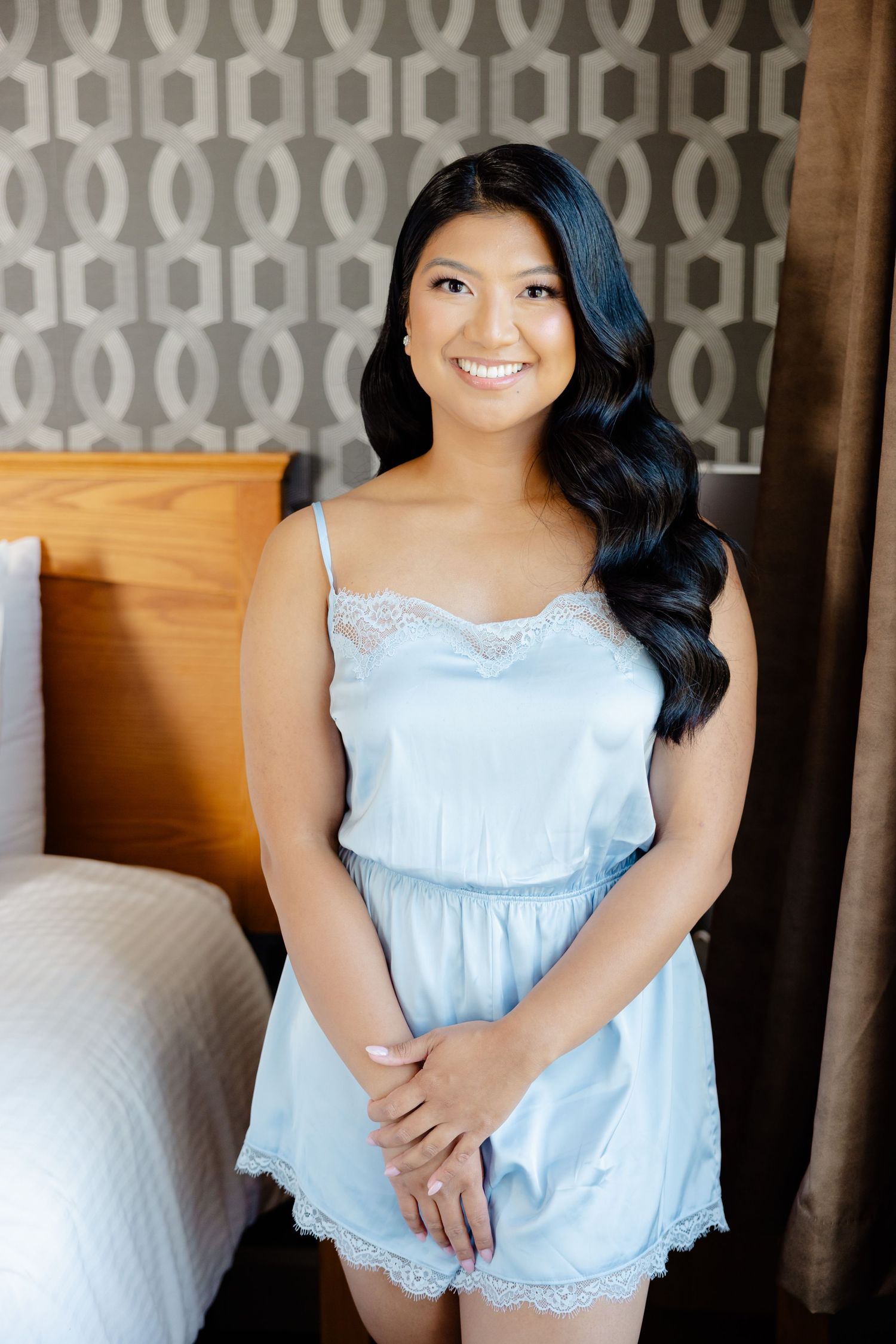 Light blue lace-trimmed romper against a geometric patterned wallpaper in a bedroom setting.
