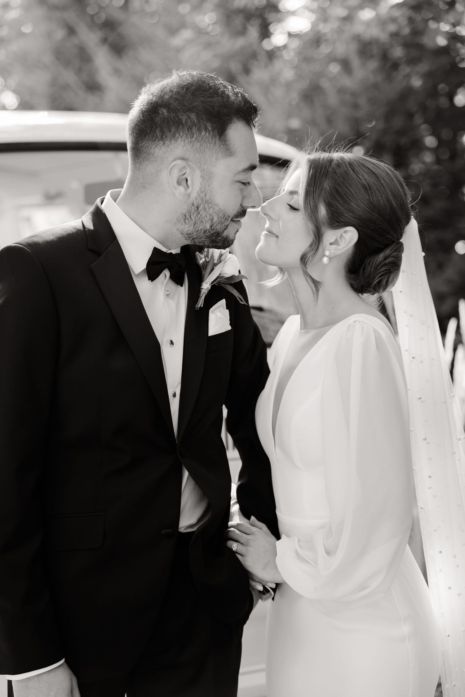 Intimate black and white portrait of wedding couple sharing romantic moment outdoors.