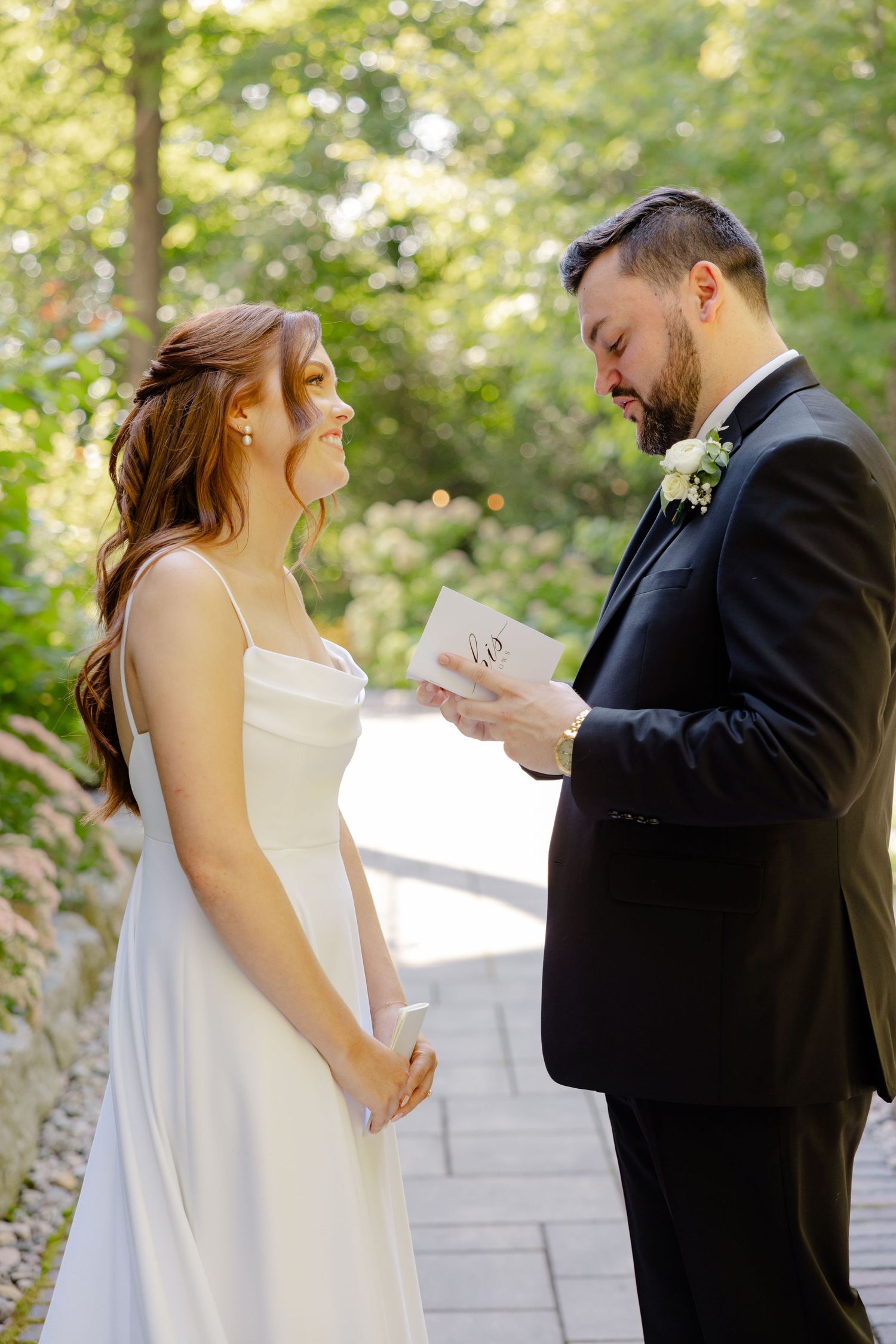 A couple shares an intimate moment during their wedding ceremony on a stone pathway surrounded by greenery.