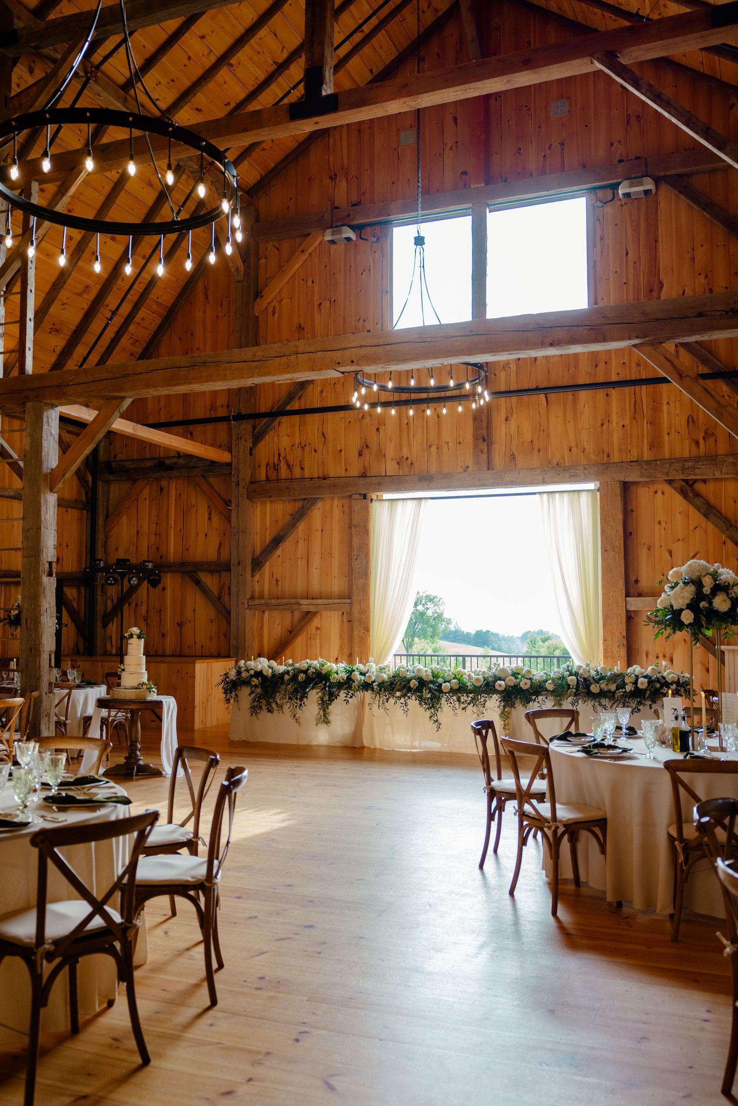Rustic barn wedding reception venue with wooden beams, string lights, and elegant table settings.