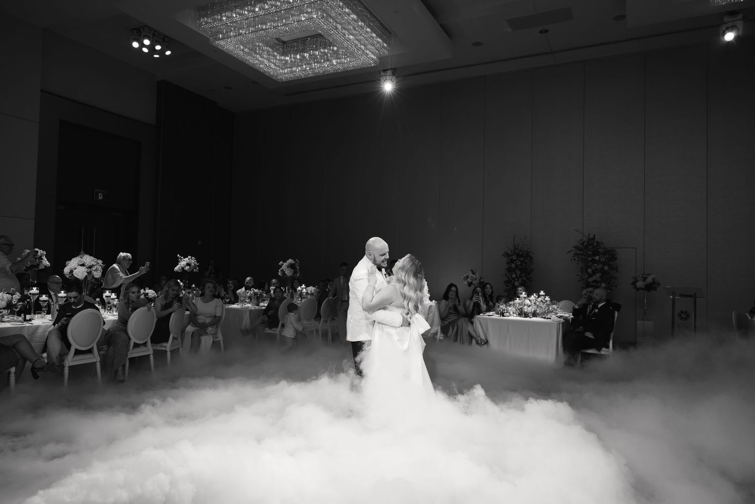 Black and white photo of couple's first dance with dramatic fog effect at reception.