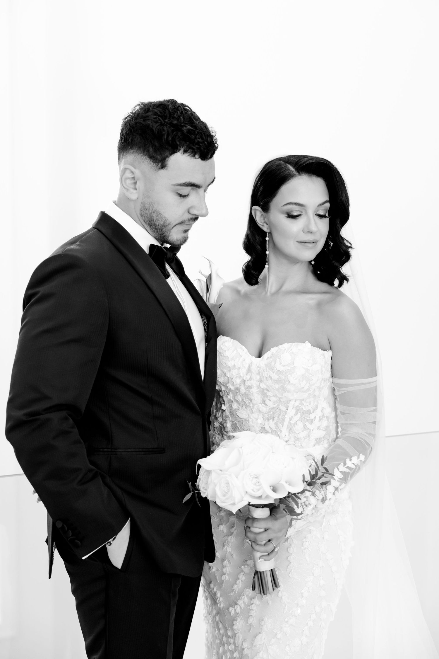 Black and white portrait of wedding couple with bride holding white rose bouquet.